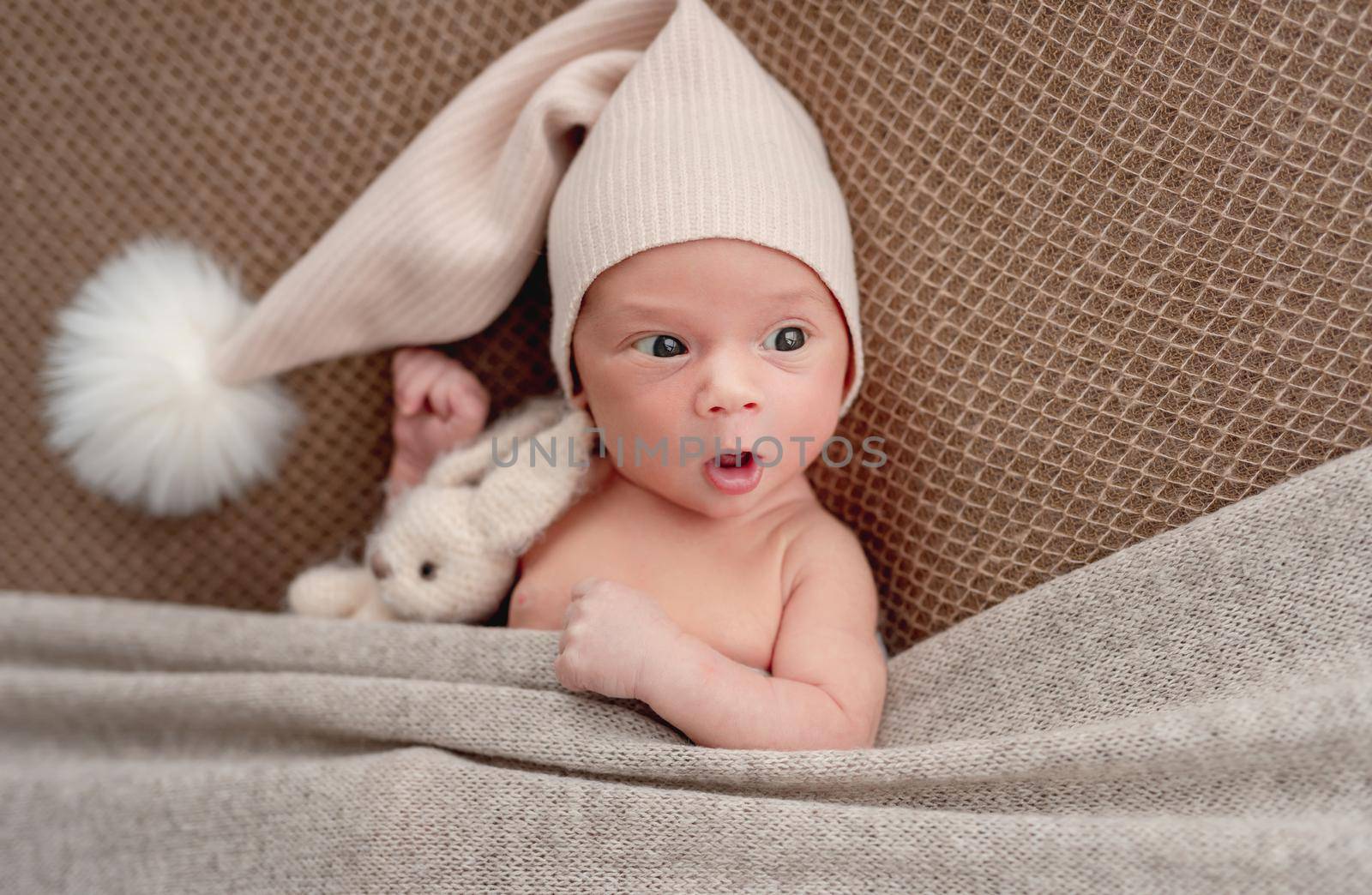 Cute sleepless newborn in funny hat looking to side