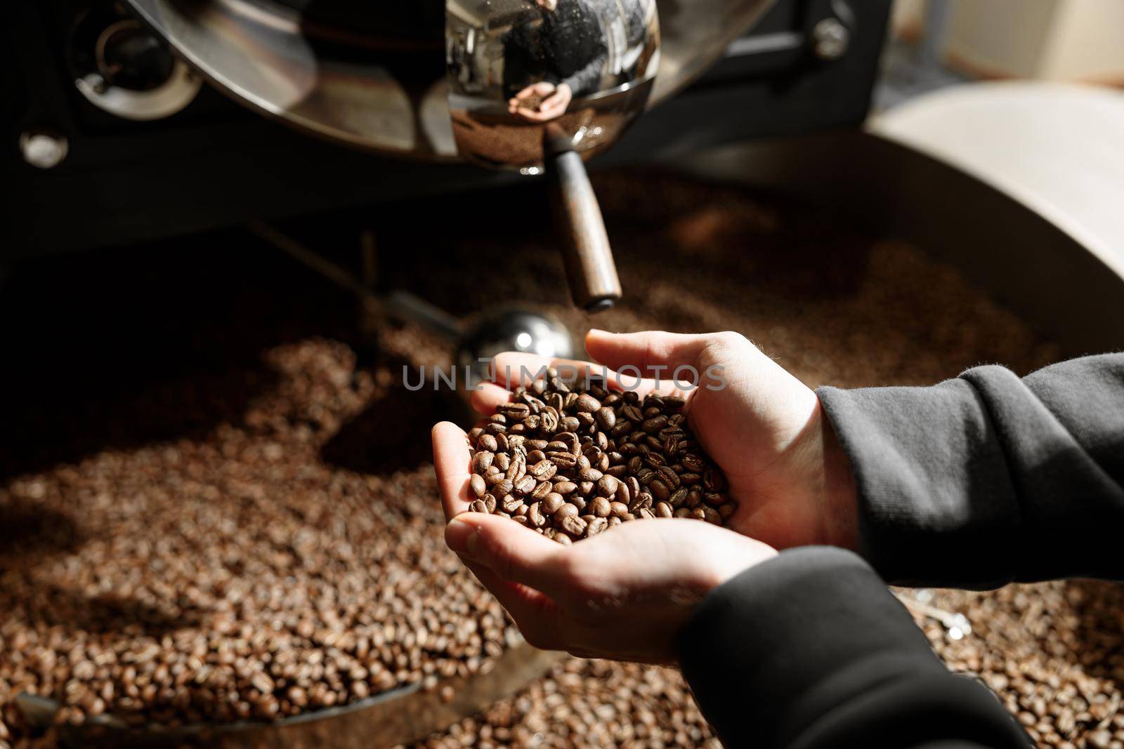 Young specialist worker is roasting coffee in hangar