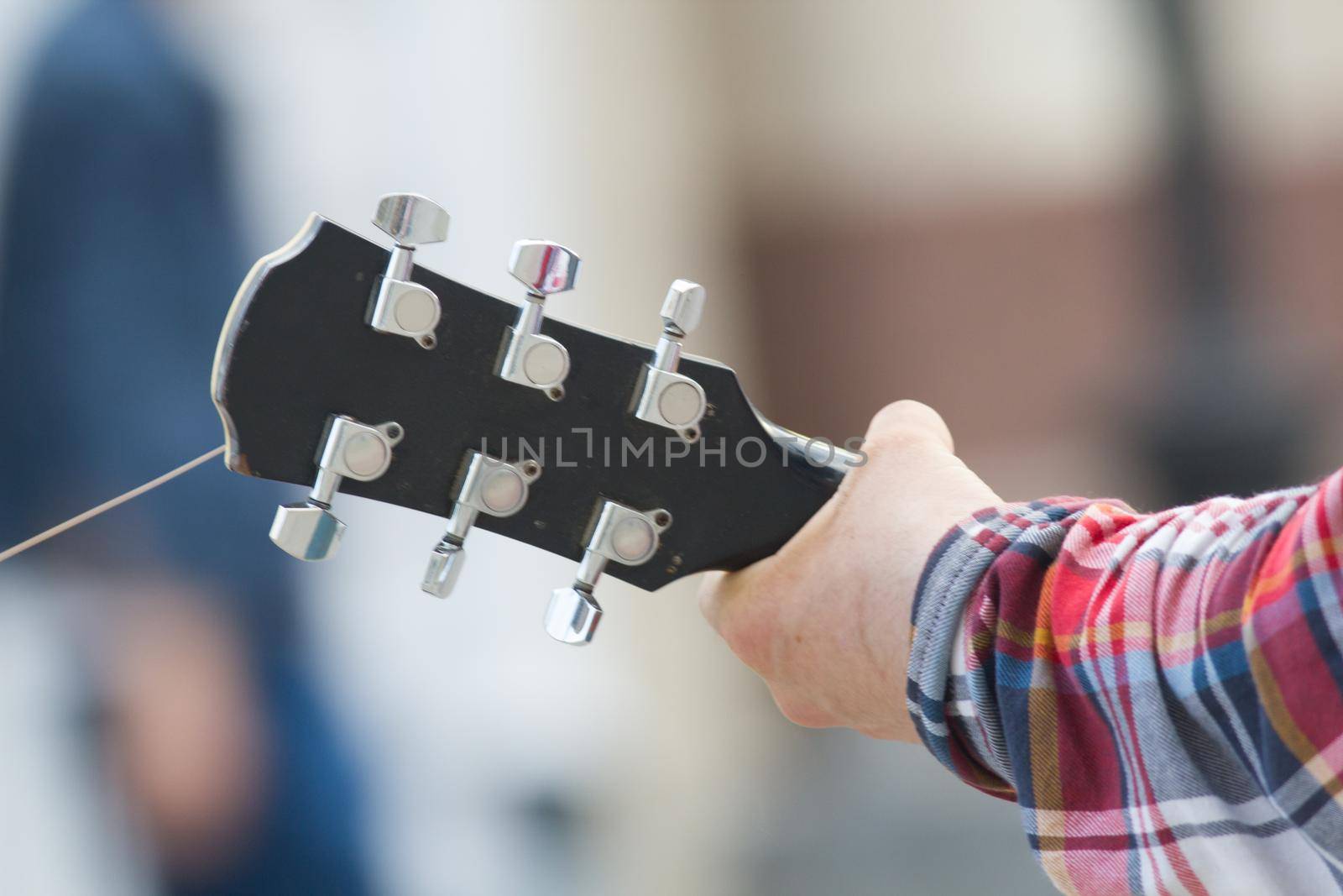 Hand of man playing acoustic guitar at the street, close up