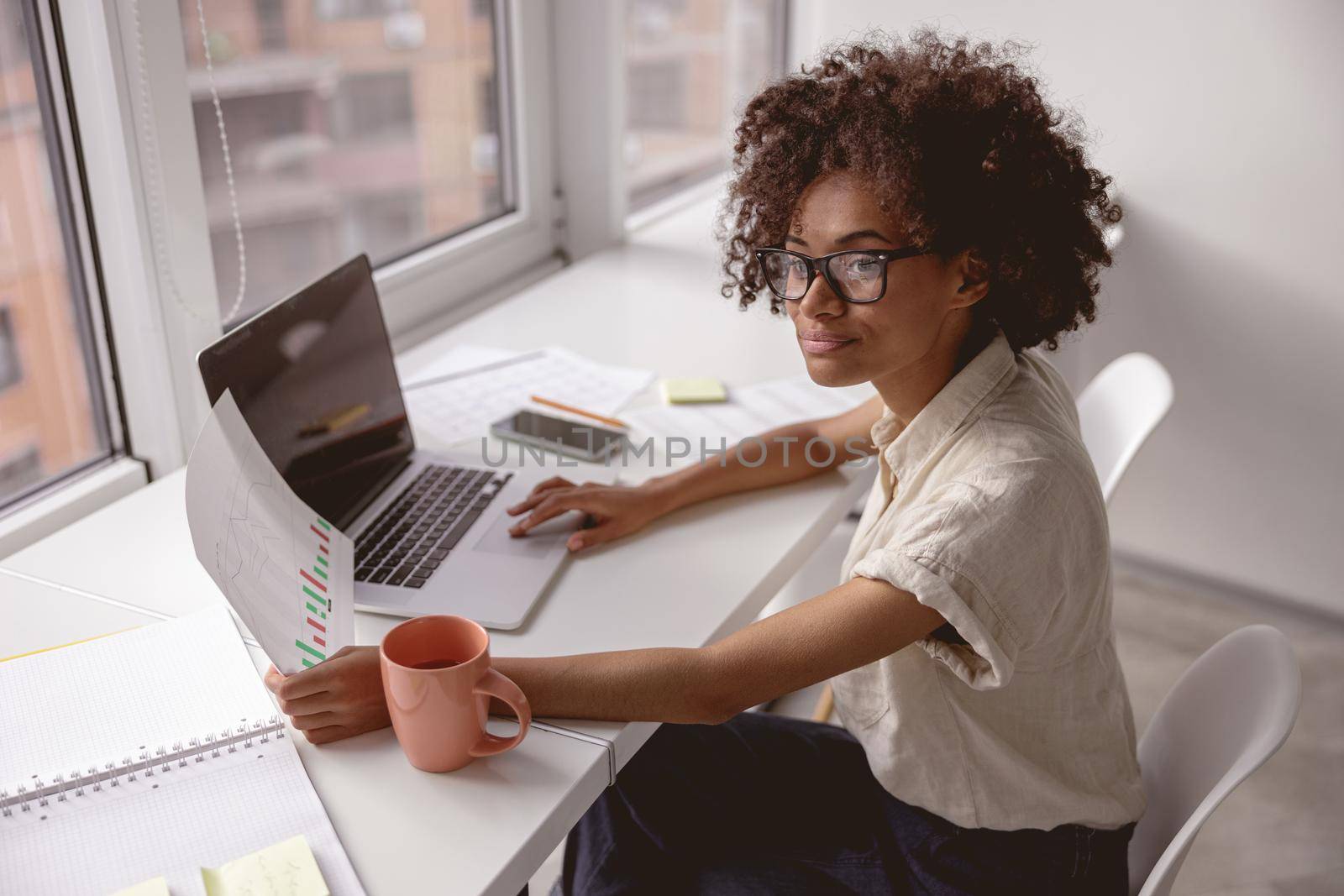 Portrait of cheerful business African-American woman working on laptop