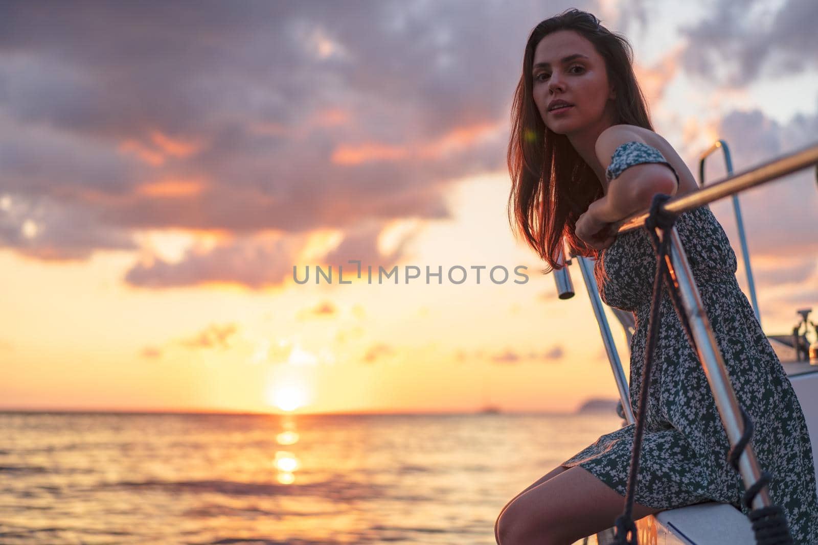 Young attractive woman sitting on the deck of the yacht and enjoying sunset