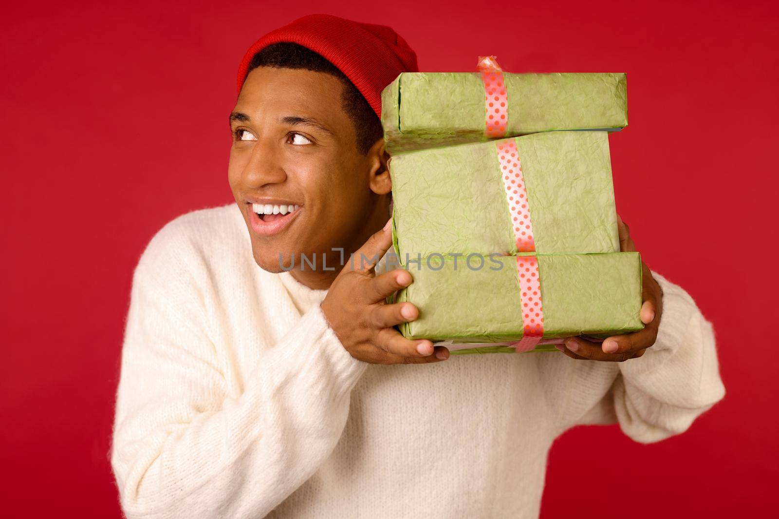 Xmas presents. Smiling dark-skinned young guy with gift boxes in hands