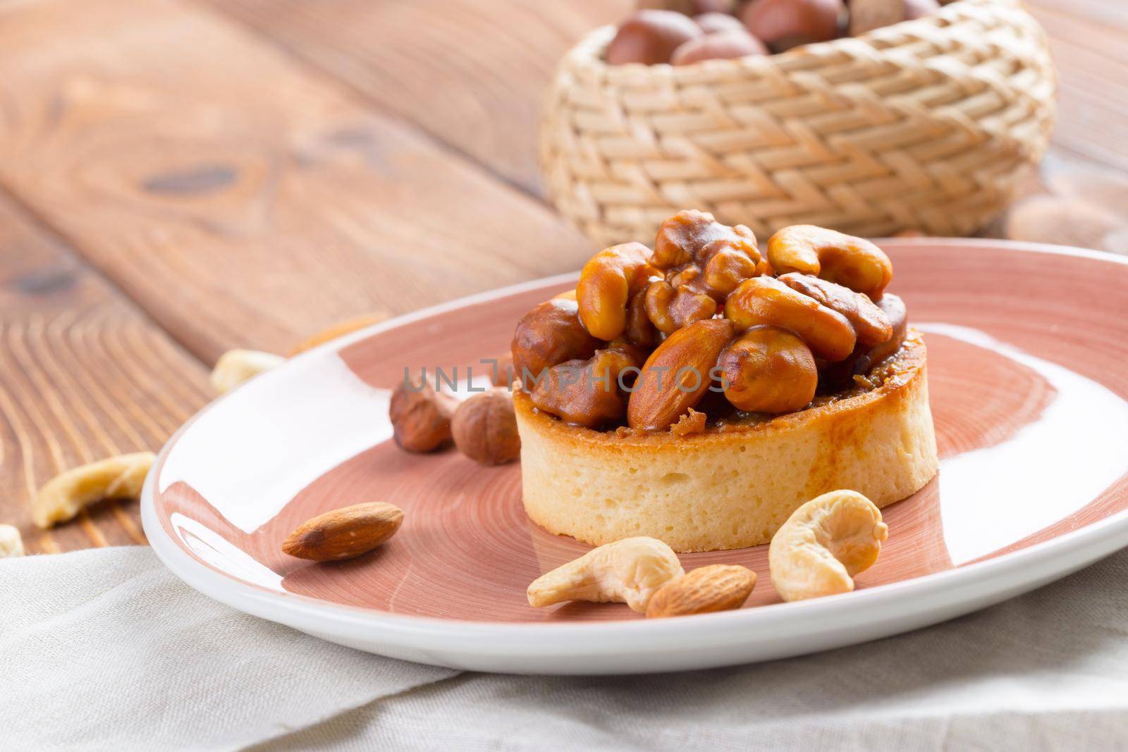 Tart with nuts on pink plate close up. Pastry