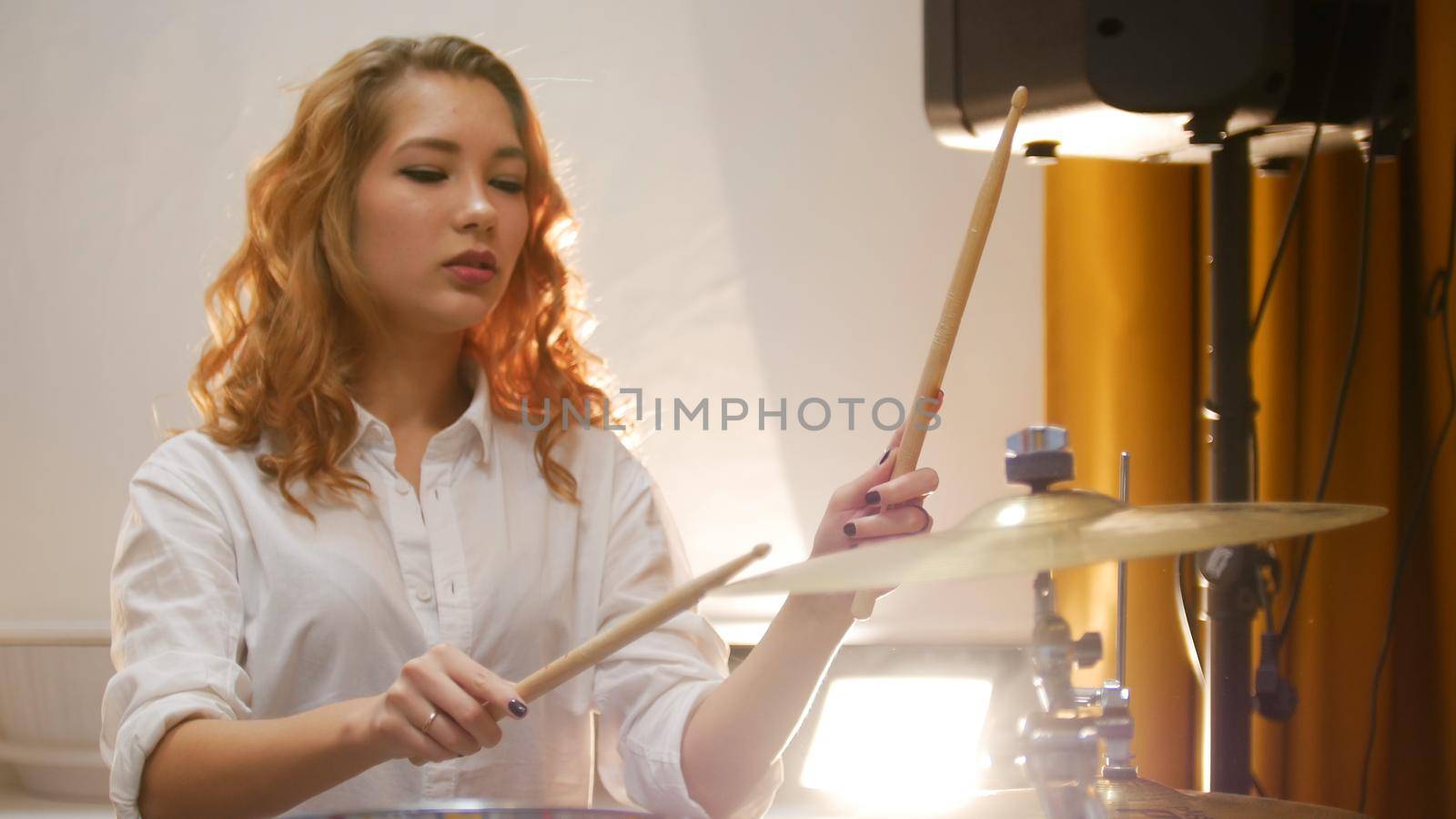 Pretty redhead girl playing drums in studio. Portrait