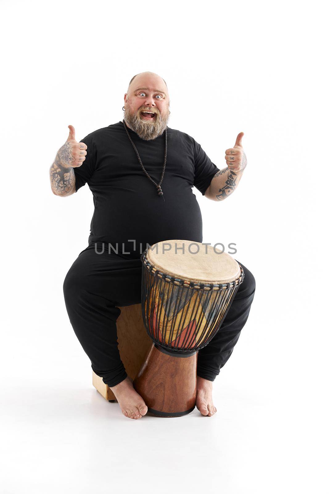 Funn caucasian bearded tattoed man is posing on white background