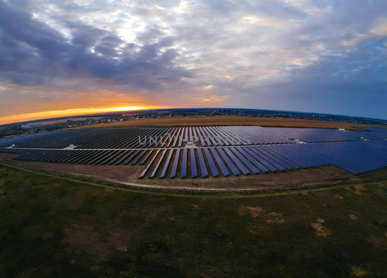 Aerial panorama view of large solar panels at a solar farm at bright summer sunset. Solar cell power plants, colorful photo