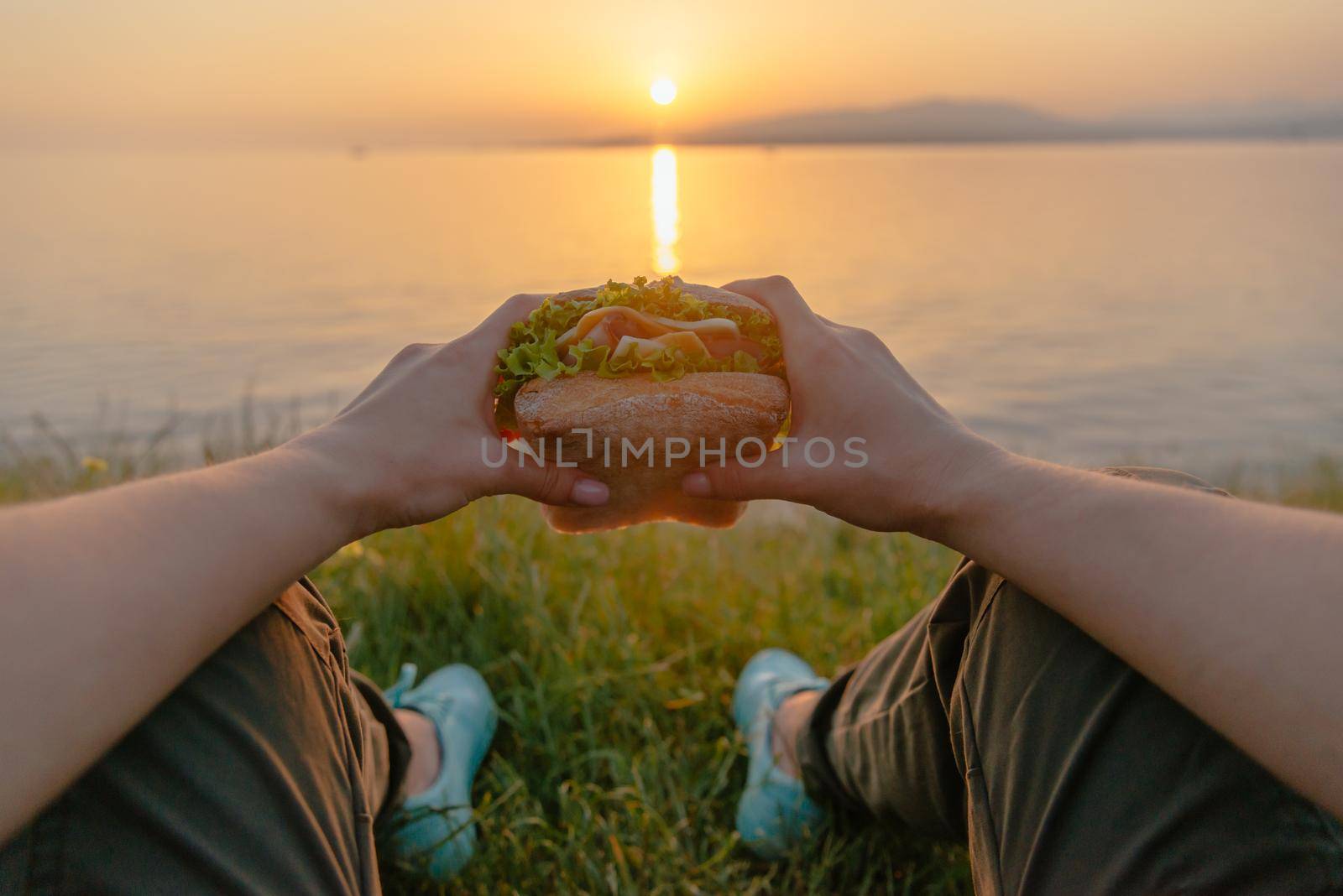 POV image of woman with burger by the sea. by alexAleksei