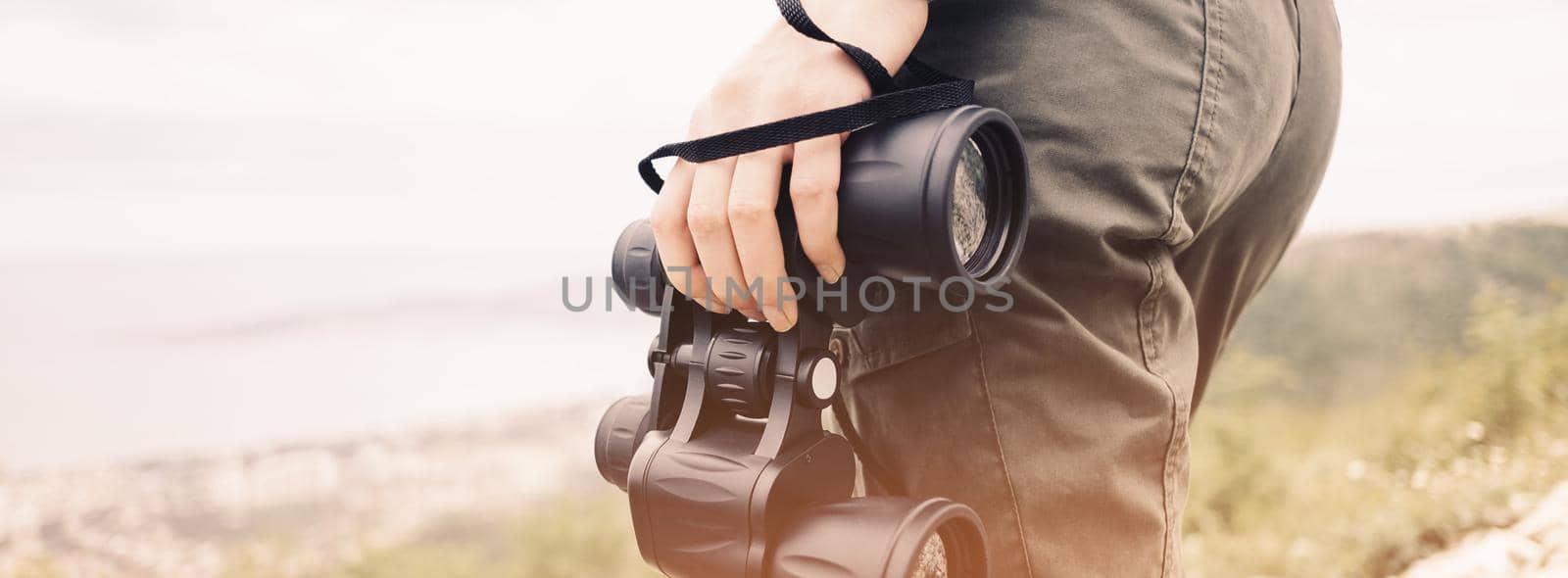 Unrecognizable woman standing with binoculars in summer mountains, close-up.