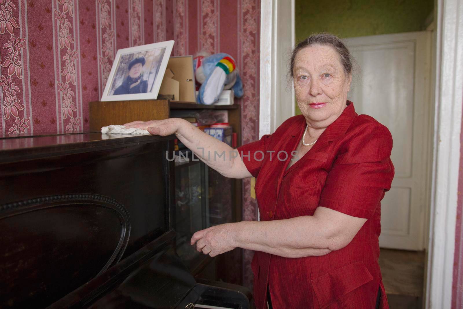 Old lady wiping the dust off the piano with a cloth, active ageing