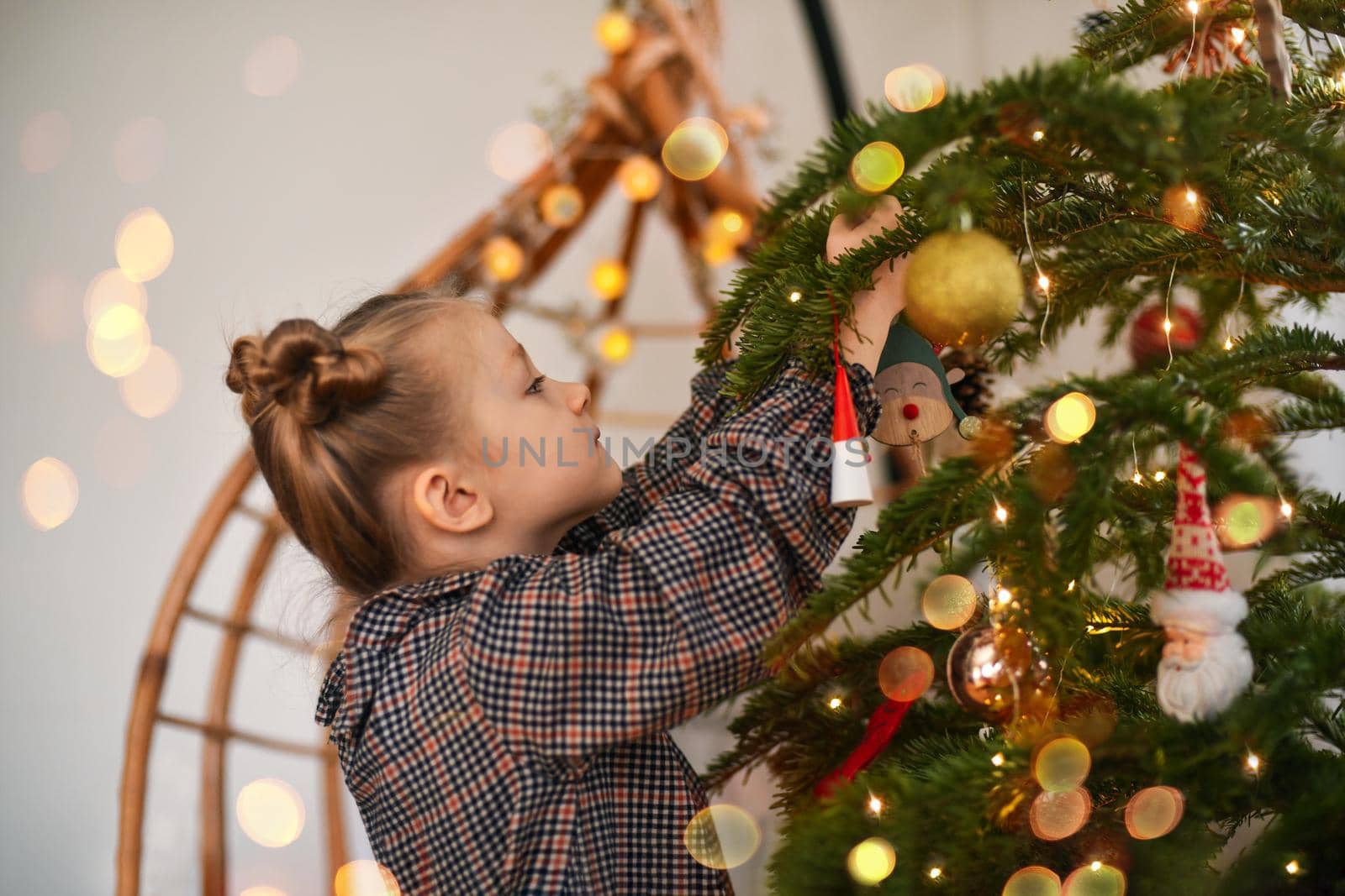 A small girl decorates a Christmas tree by Godi