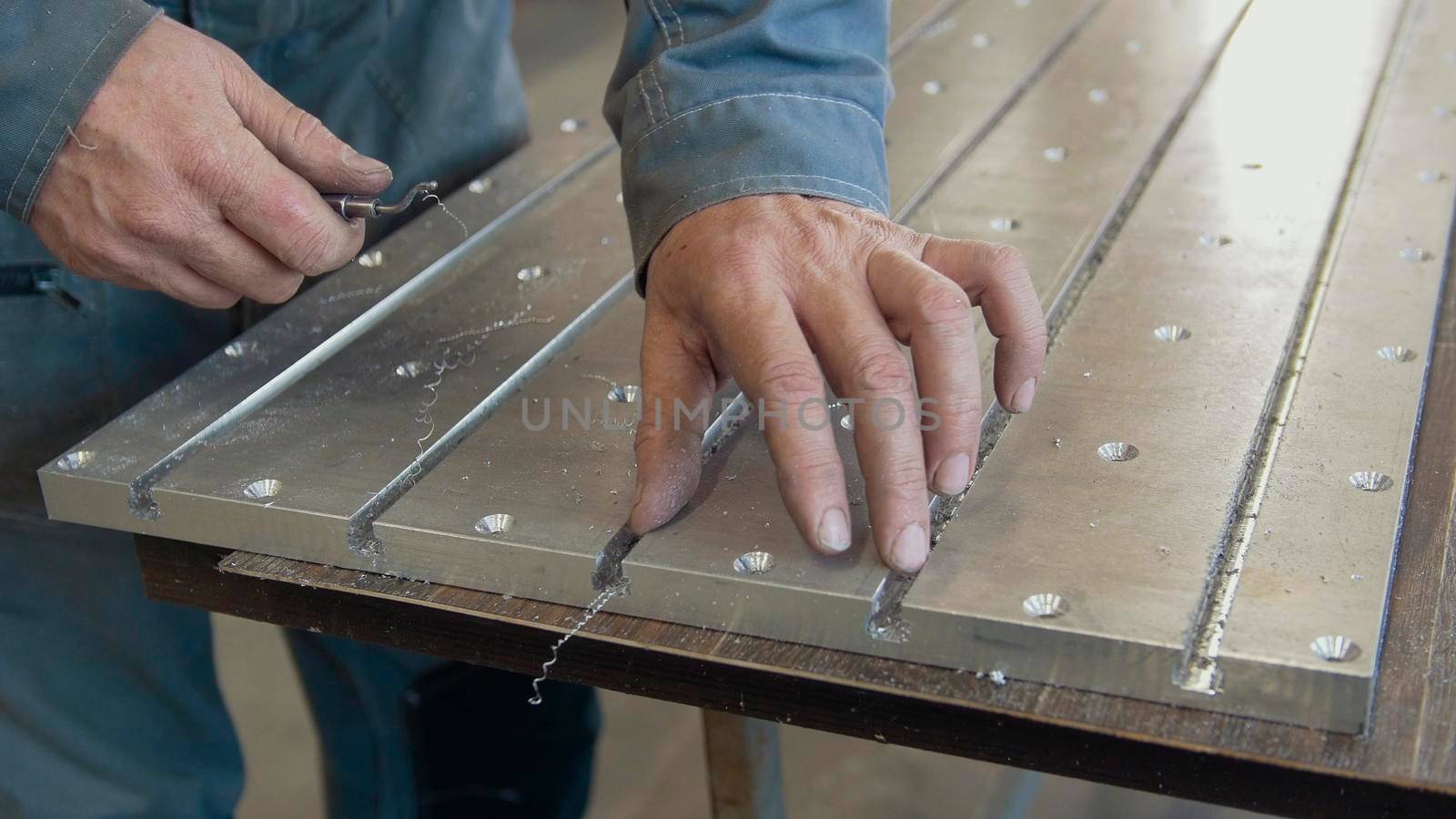 Male working hands grinds the metal body with a scraper, close up