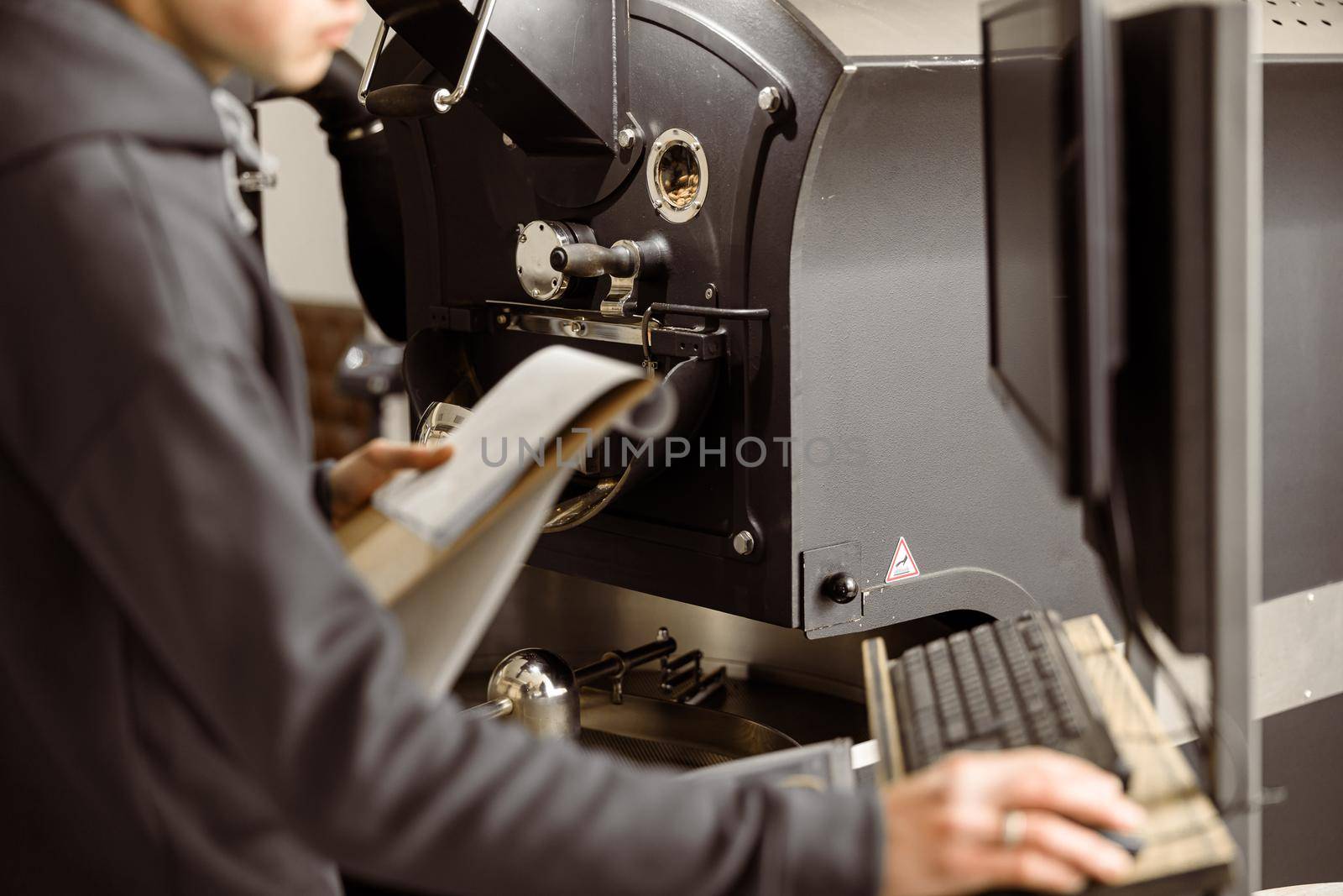 Young specialist worker is roasting coffee in hangar