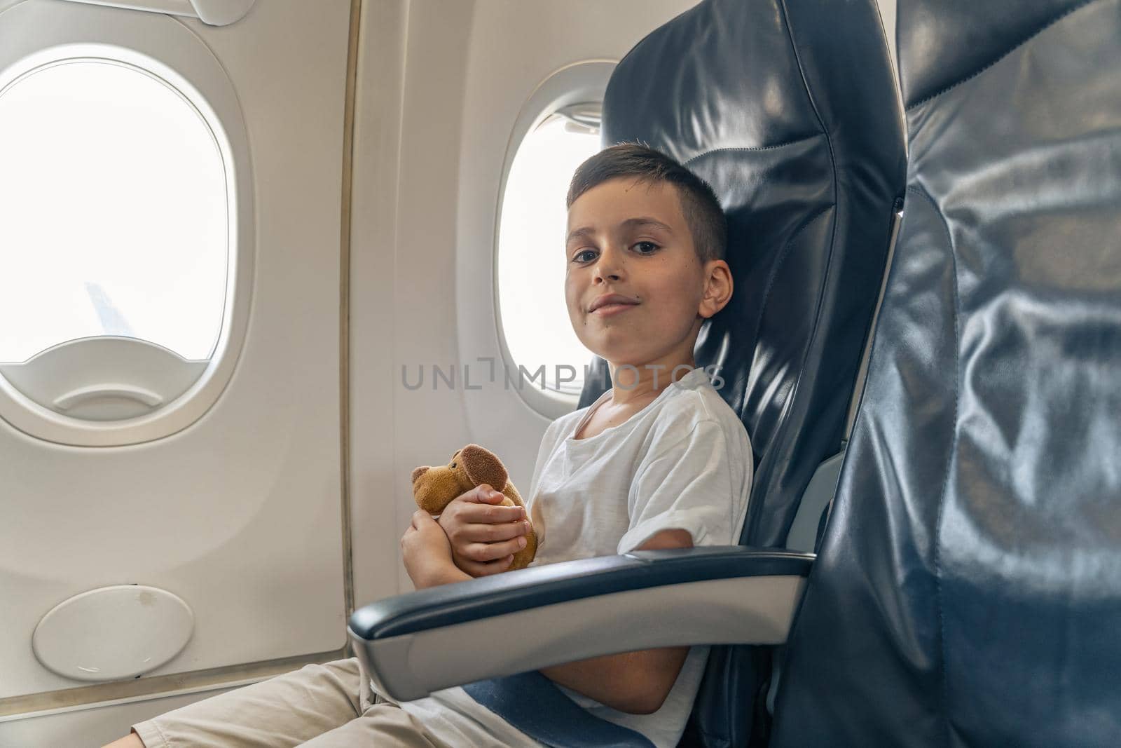 Happy cute little boy with toy in airplane during the travelling. Copy space