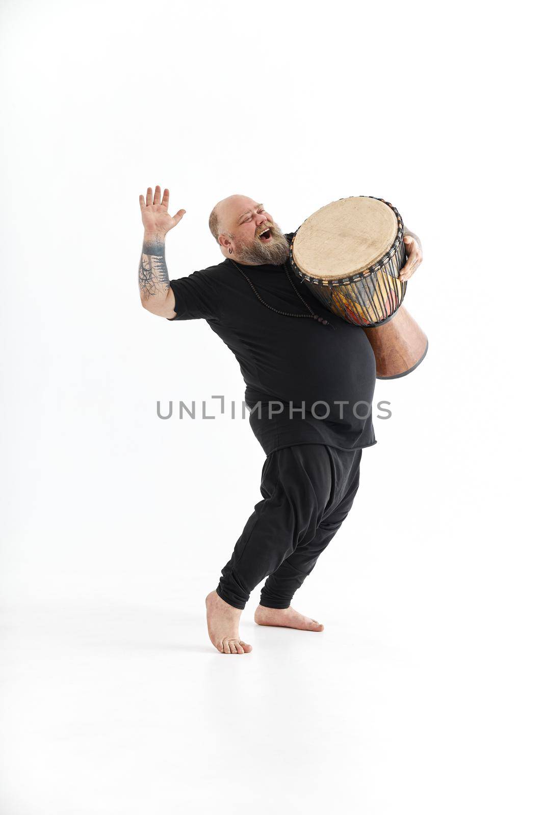 Funn caucasian bearded tattoed man is posing on white background