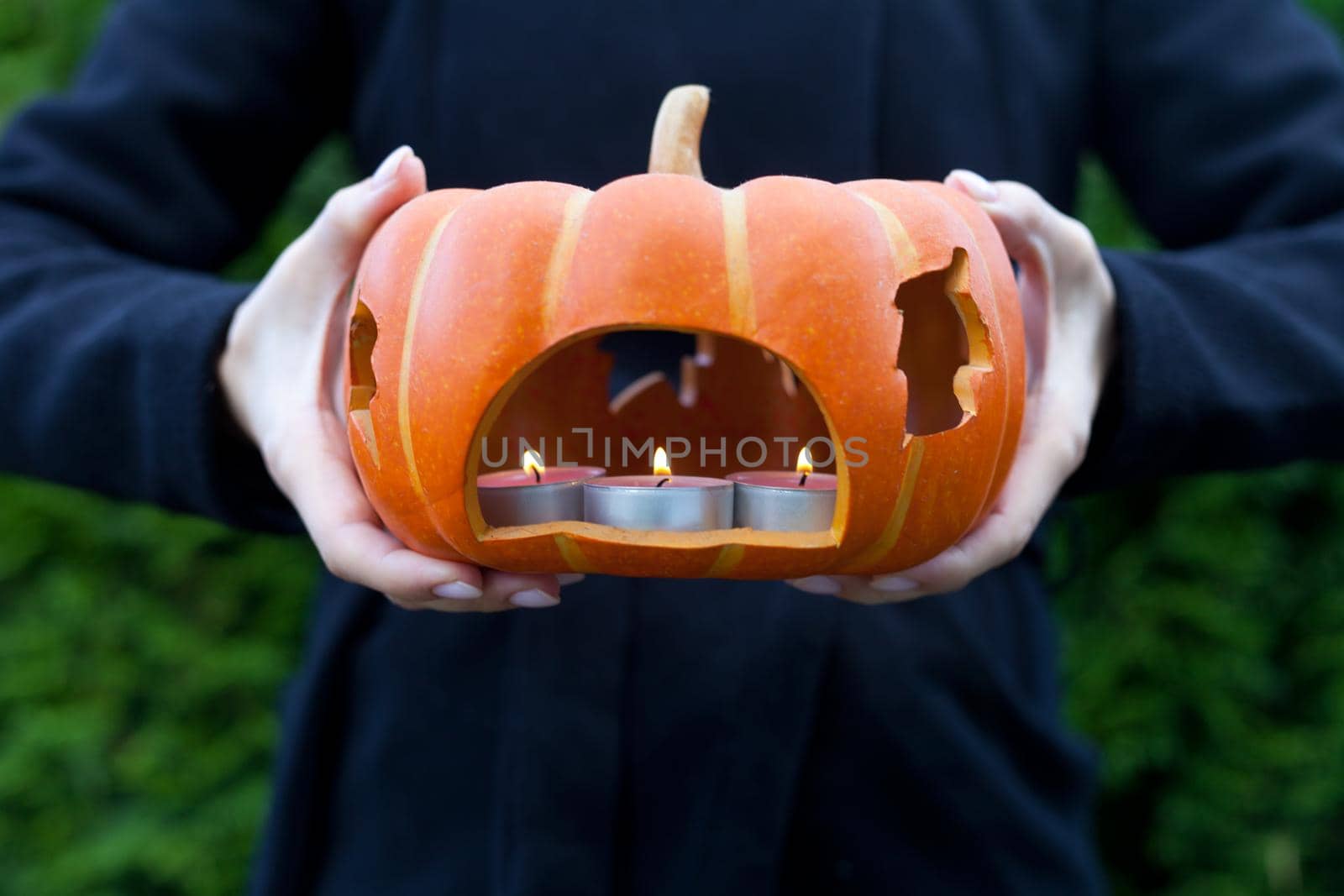 pumpkin with candle on woman hands close up-holidays, halloween, decoration and people concept