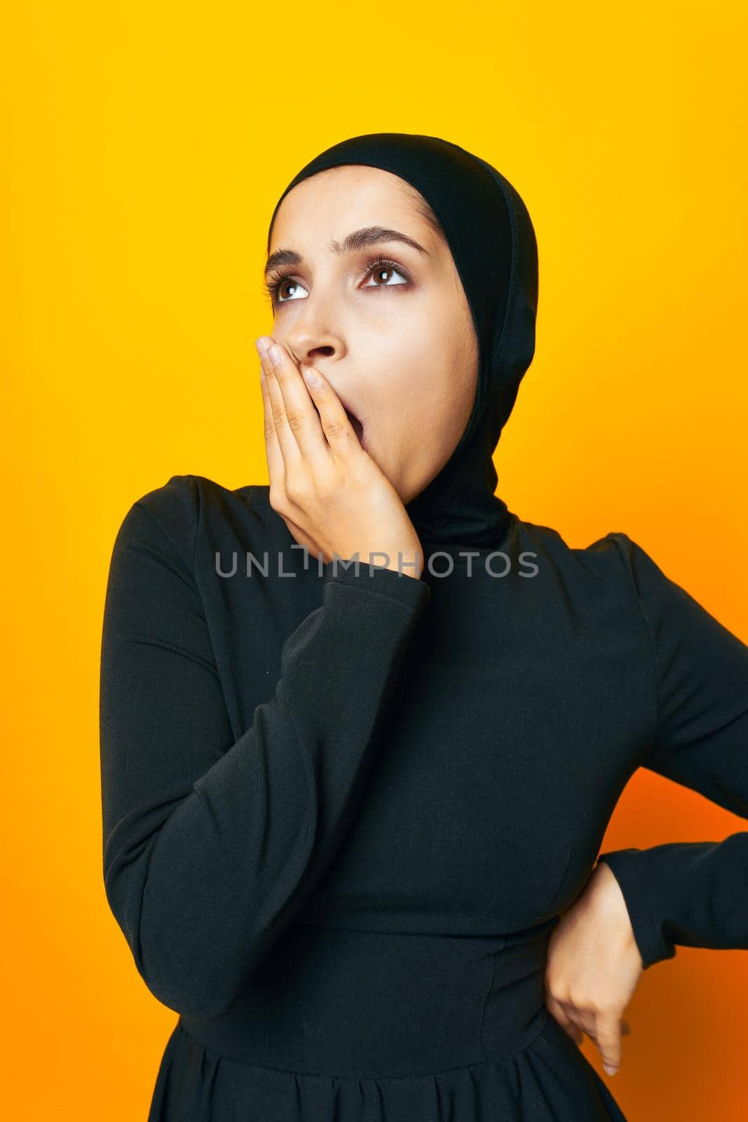 pretty woman in black hijab posing fashion hand gesture yellow background. High quality photo