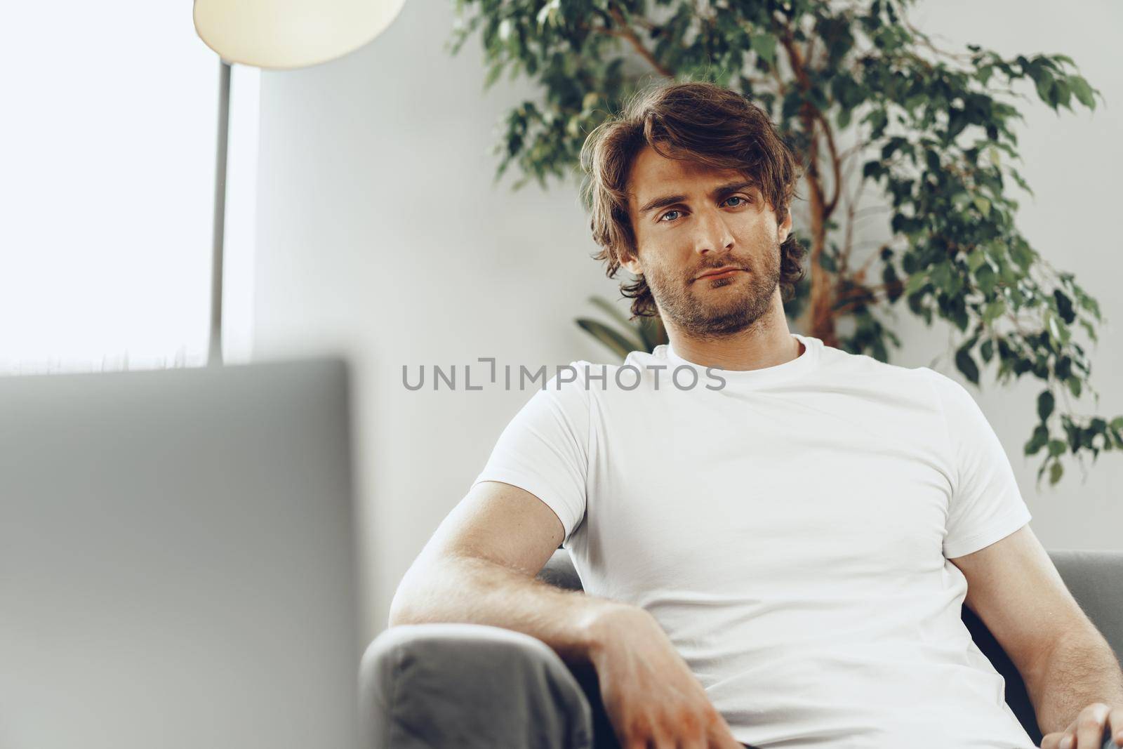 Relaxed casual man sitting on the sofa and looking at camera, man portrait