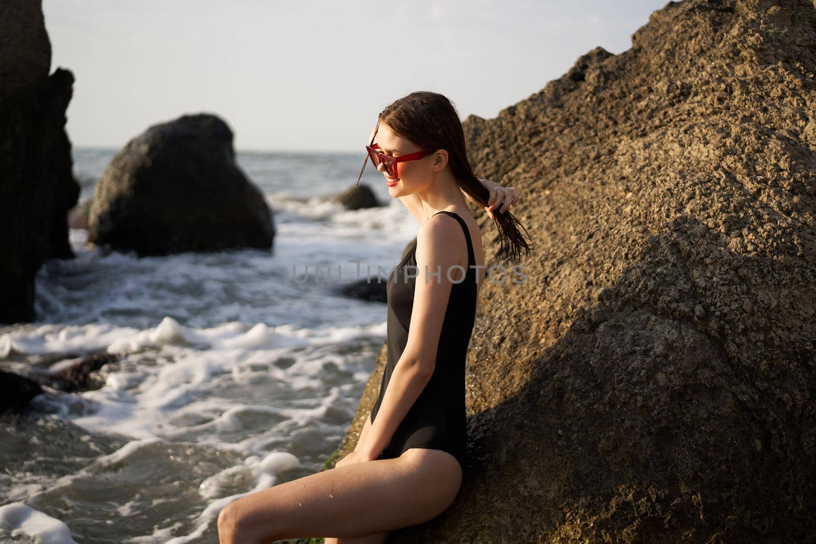 woman in black swimsuit rocks posing oceans. High quality photo