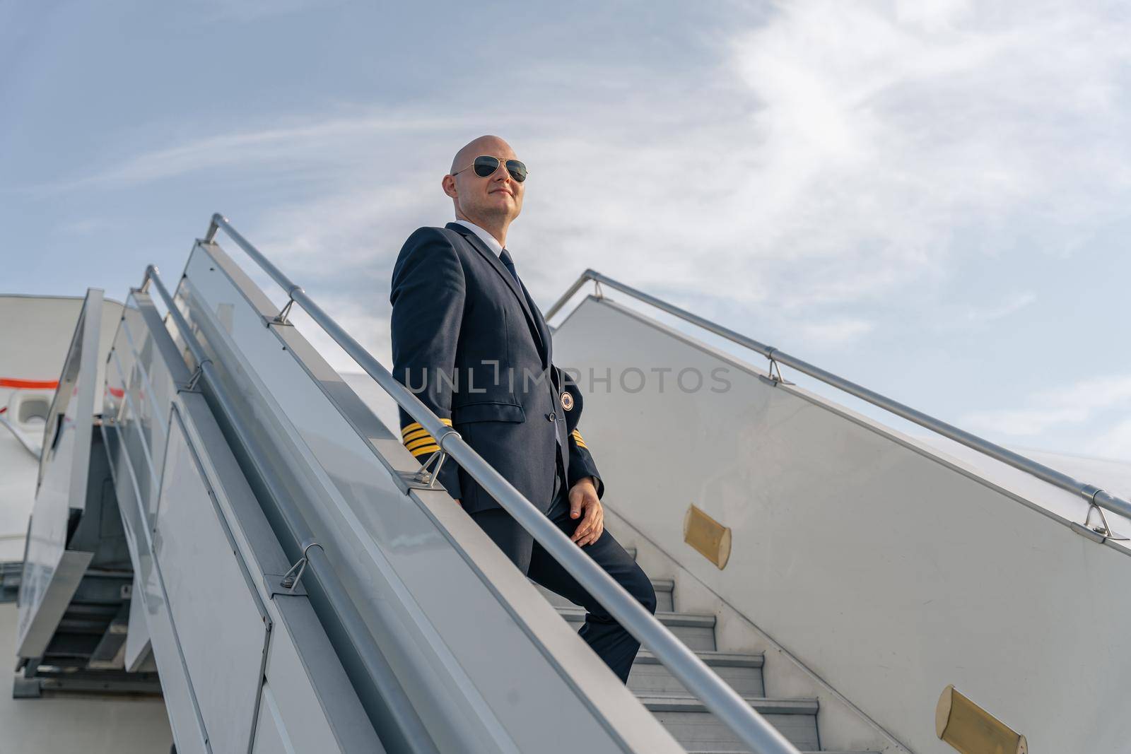Professional pilot in sunglasses on plane ladder by Yaroslav_astakhov
