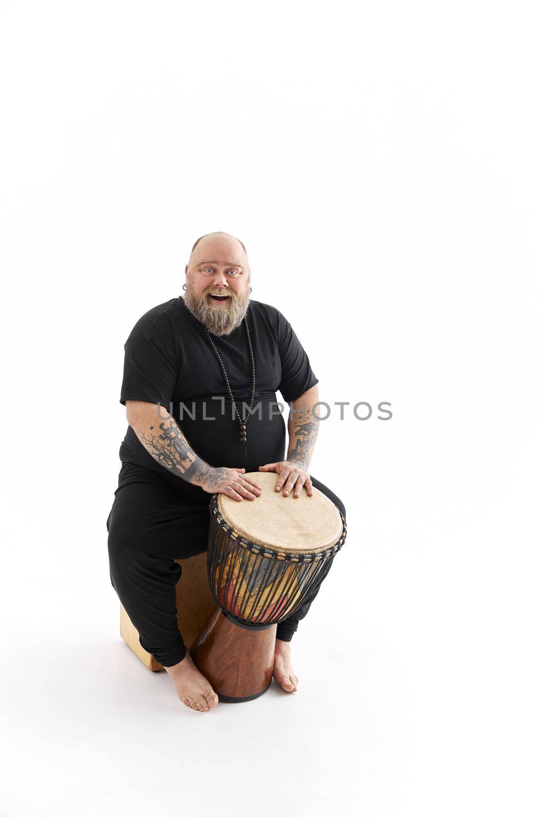 Funn caucasian bearded tattoed man is posing on white background