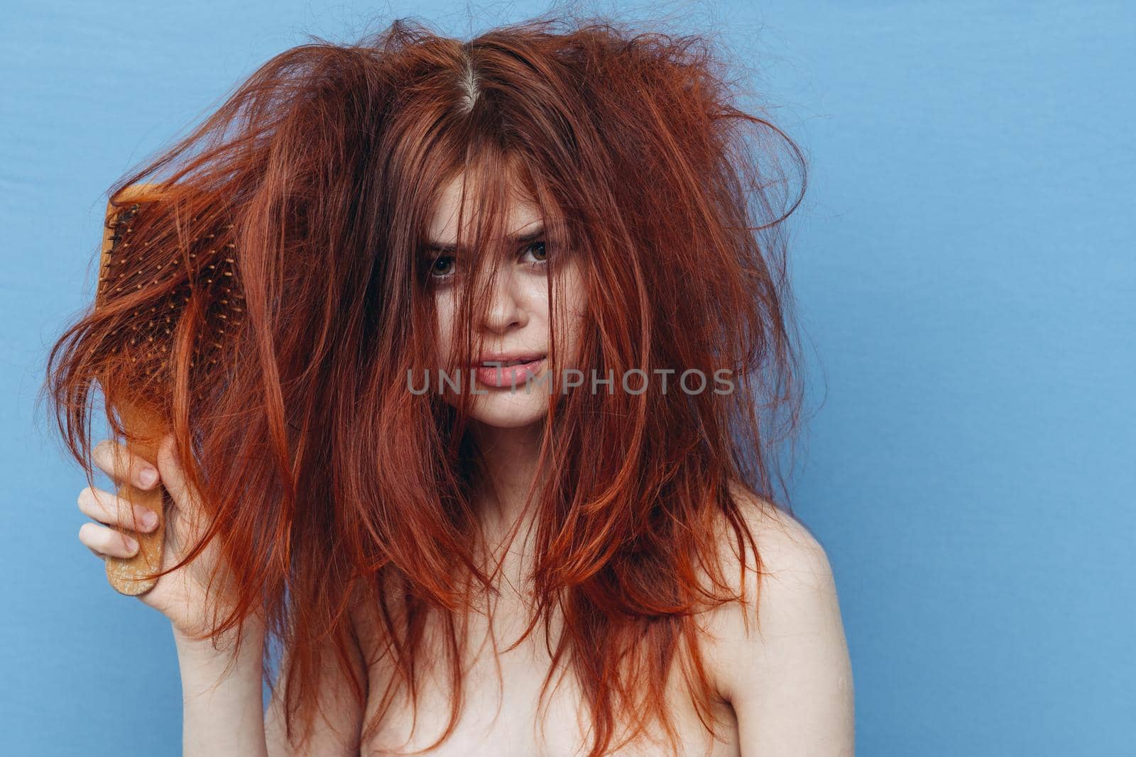 woman with red hair comb care blue background. High quality photo