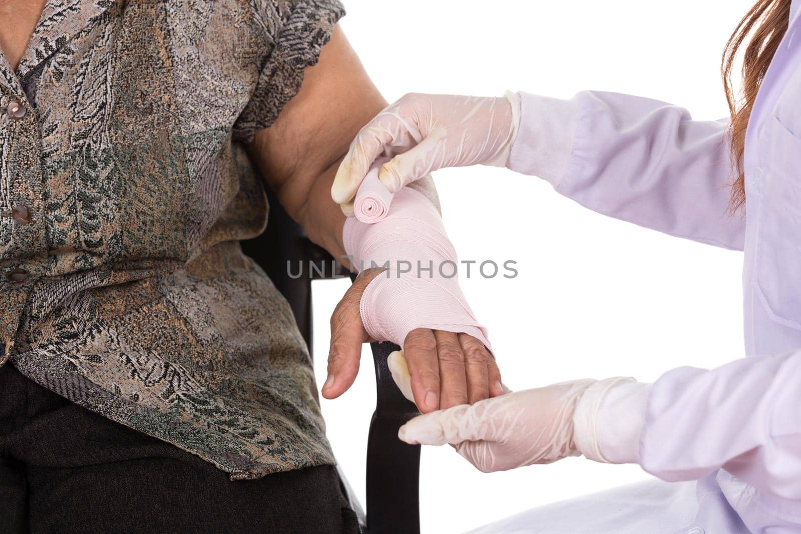 Close-up female doctor is bandaging hand of senior woman patient