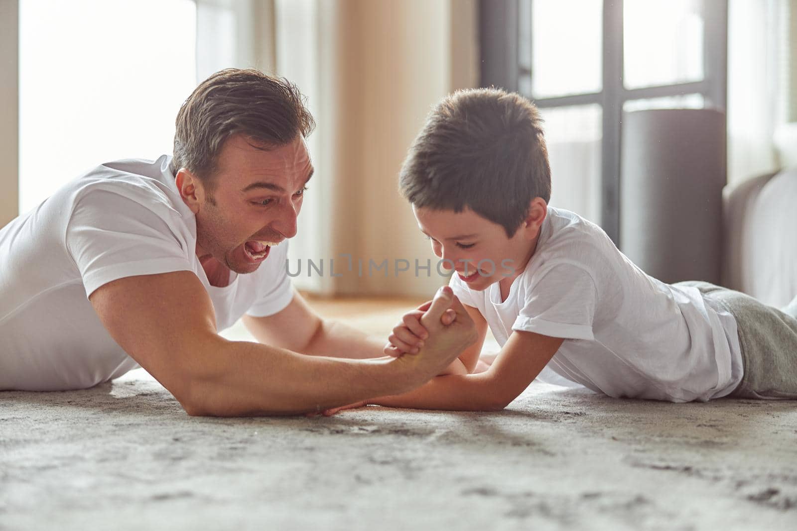 Happy man enjoying active time with son indoors by Yaroslav_astakhov