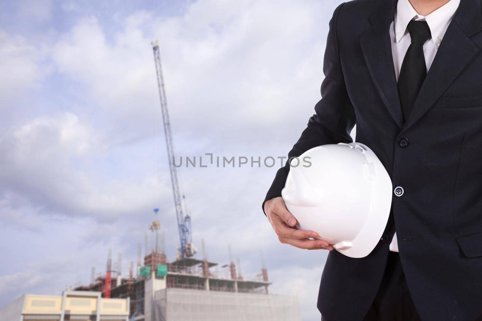 engineer holding white helmet with construction crane background