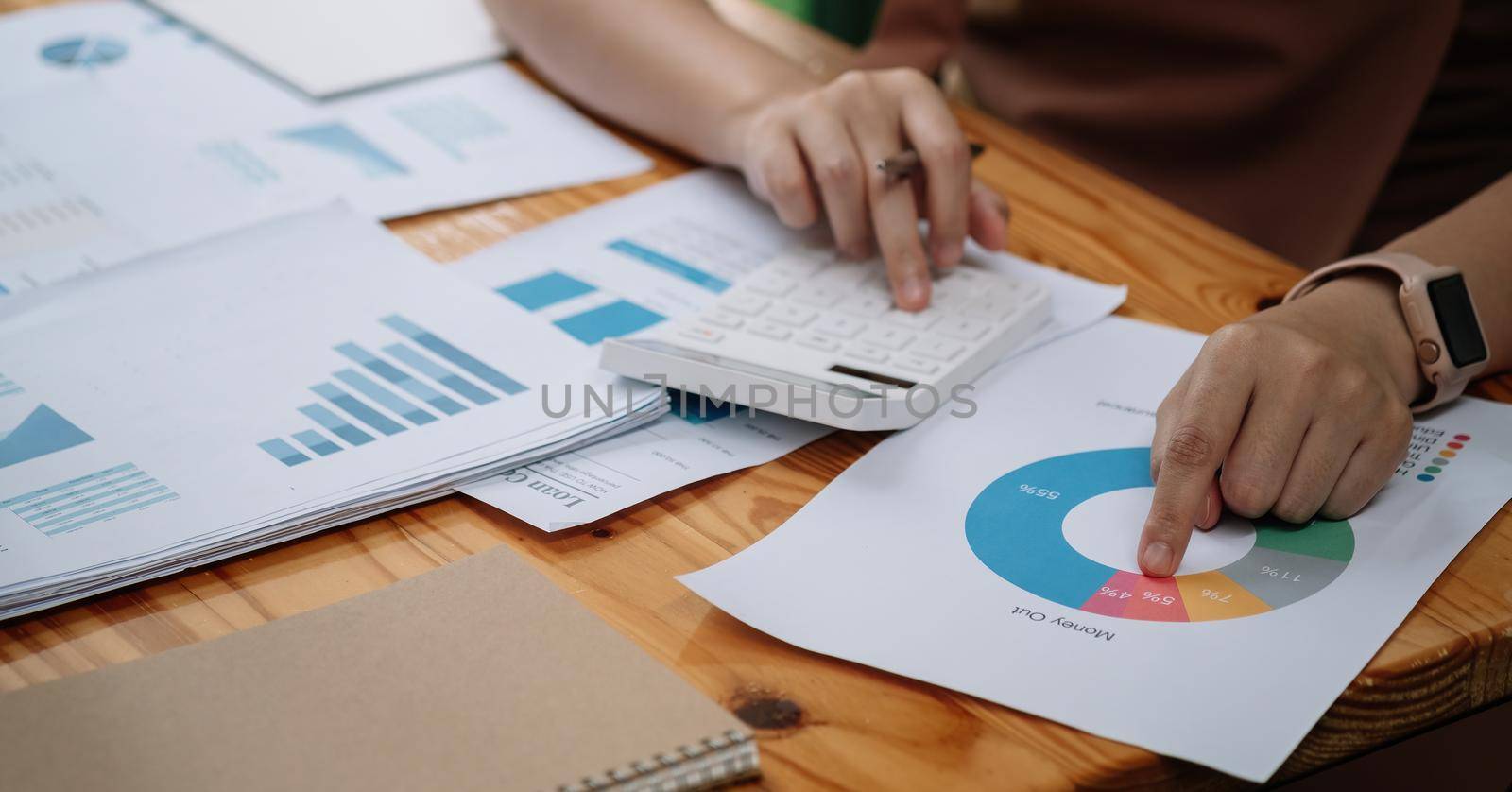 Close up of accountant hands make audit of expenses calculate charges based on paper documents. Cropped shot of woman bookkeeper work with financial report at home.