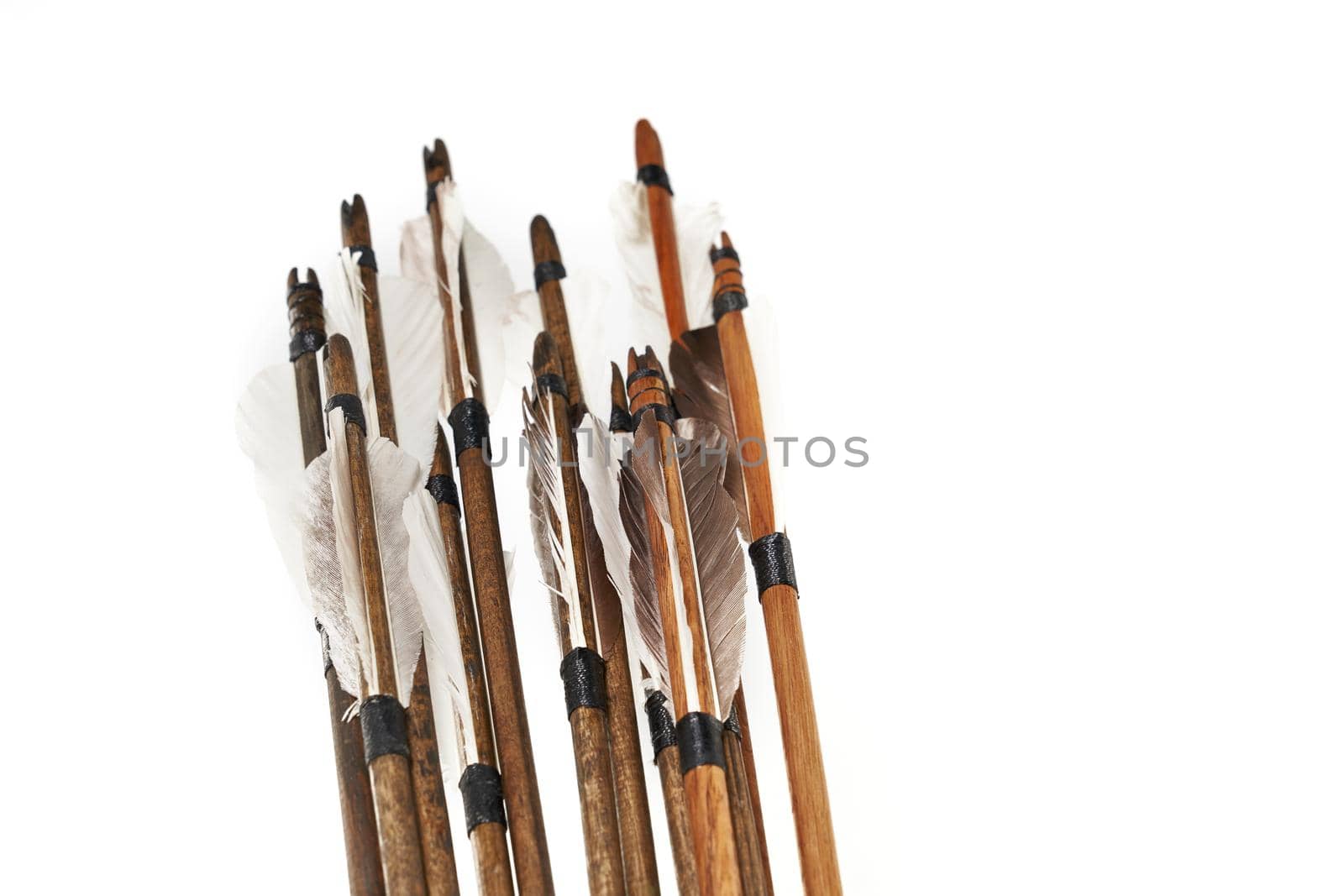 Closeup view of ancient wooden arrows with grey feathers isolated on white background. Qualitative old medieval weapon.