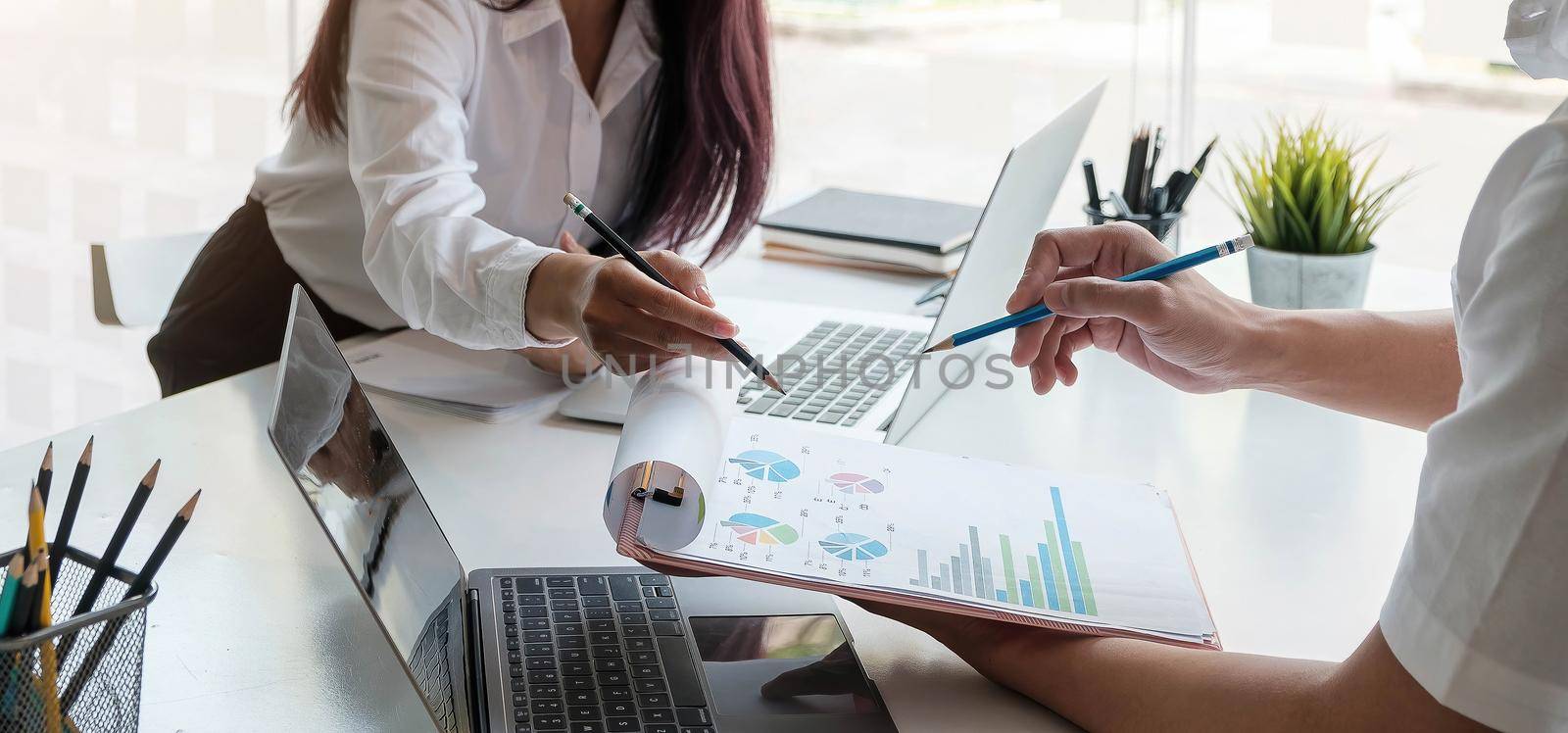 Diverse businesspeople discuss financial report in charts diagrams and graphs close up above view, business partners analysing common sales statistics presenting deal benefits at group meeting concept by wichayada