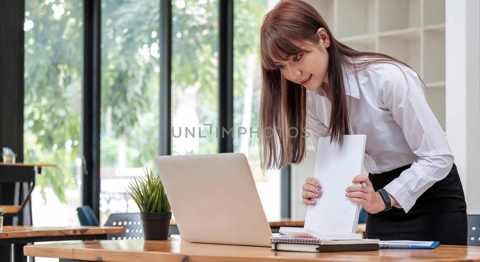 Smart businesswoman analyzing business data, reviewing profits report and working on laptop computer with calculator on desk in office, startup business, business strategy analysis concept, close up.