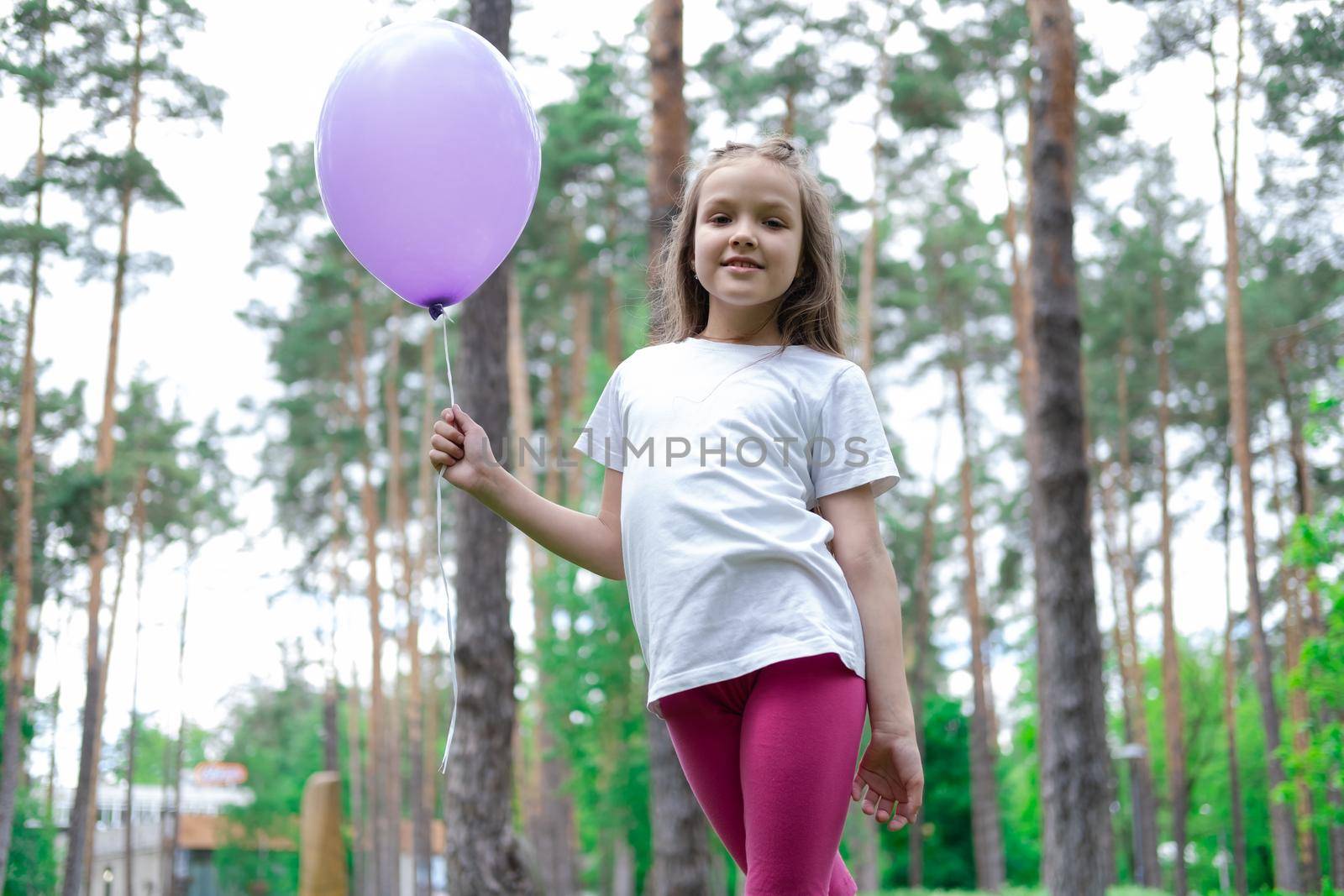 pretty girl in pink leggings and white t-shirt with purple hot air balloon in park. holliday, party, birthday, celebration. happy children.