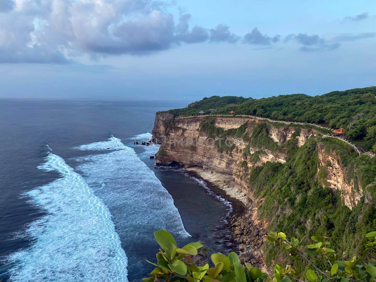 A scenic Uluwatu cliff with pavilion and blue sea in Bali - stock photo