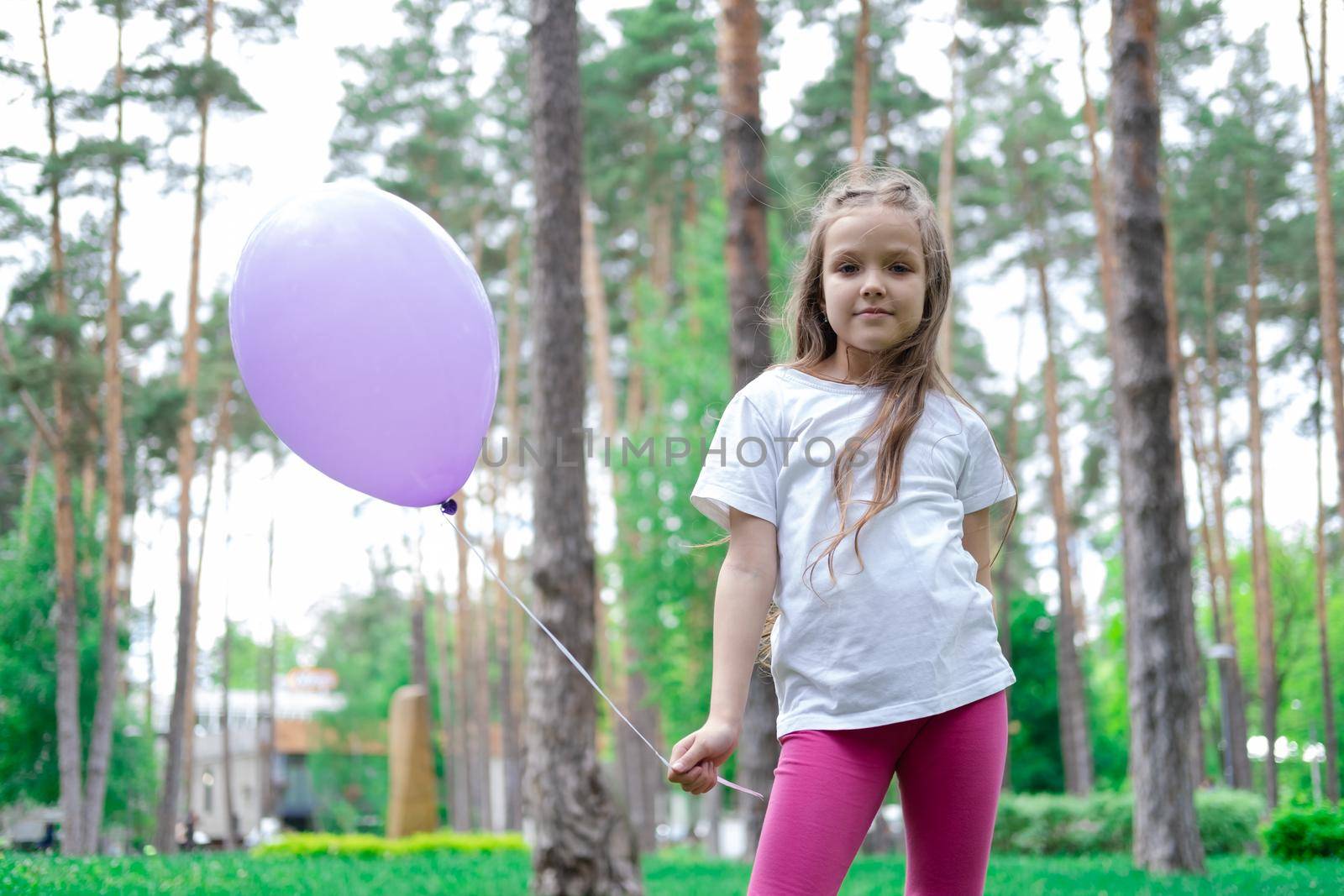 pretty girl in pink leggings and white t-shirt with purple hot air balloon in park. holliday, party, birthday, celebration. happy children by oliavesna