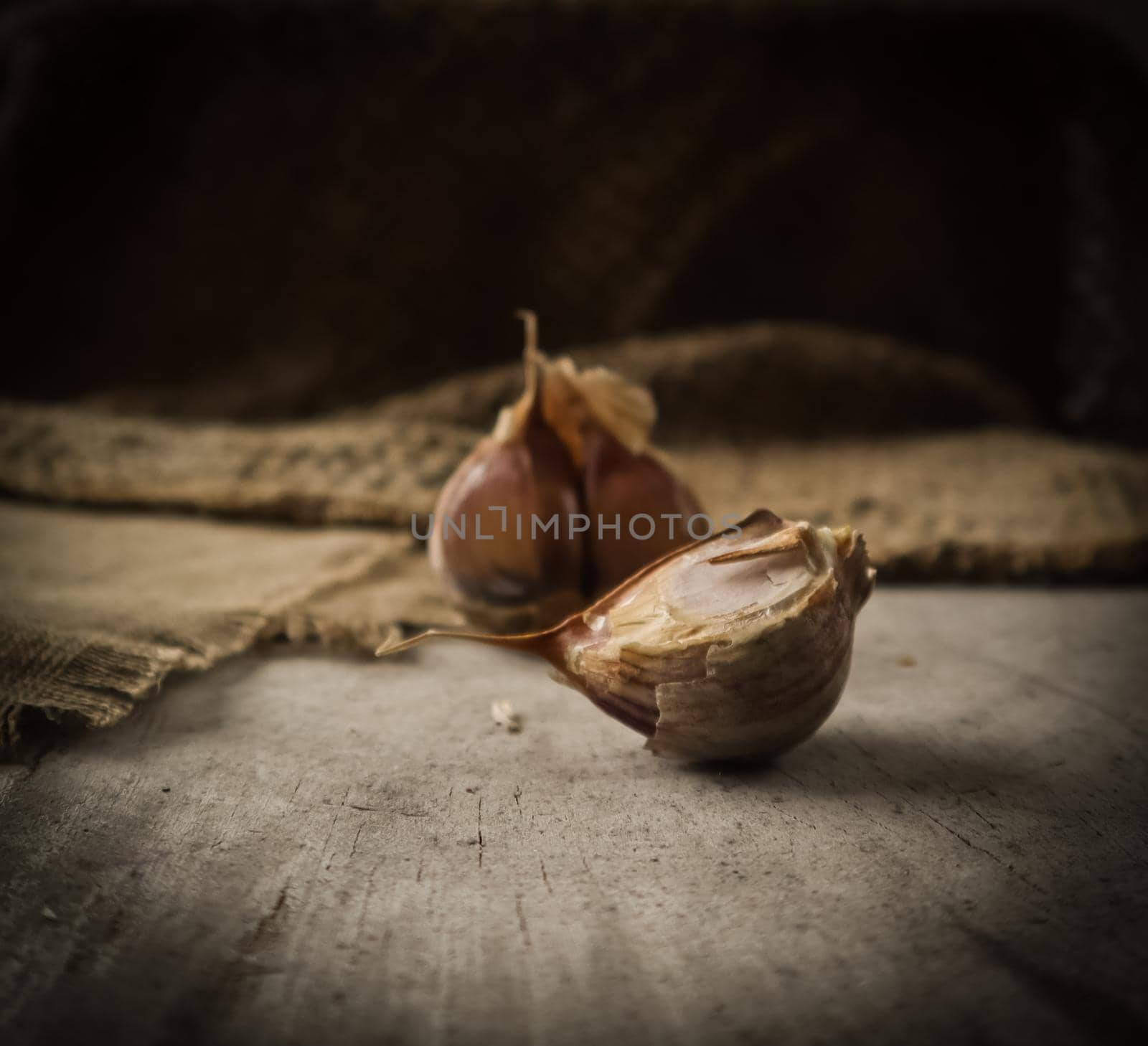 Garlic cloves and natural linen napkin on rustic wooden background