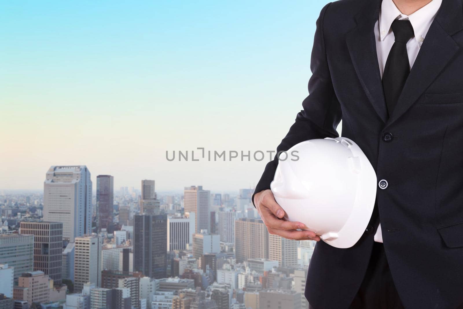 engineer holding white helmet with city background by geargodz