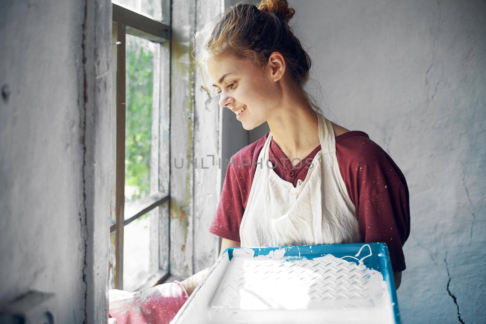 woman in apron painter repair painting window. High quality photo