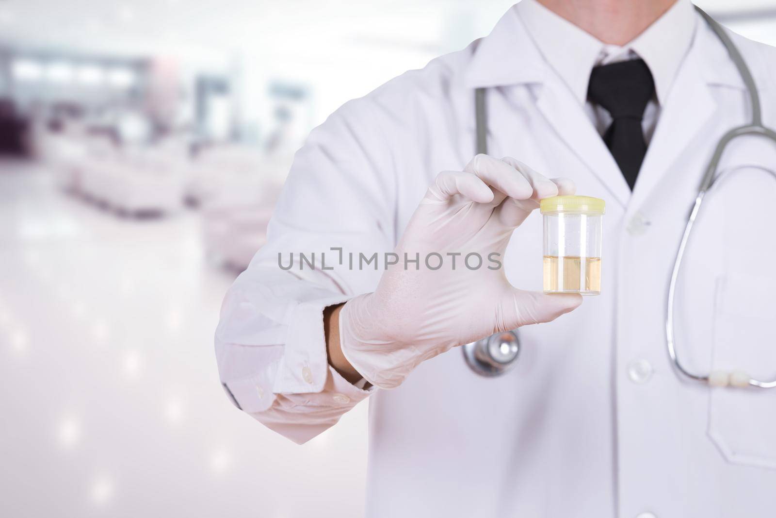 doctor's hand holding a bottle of urine sample in hospital by geargodz