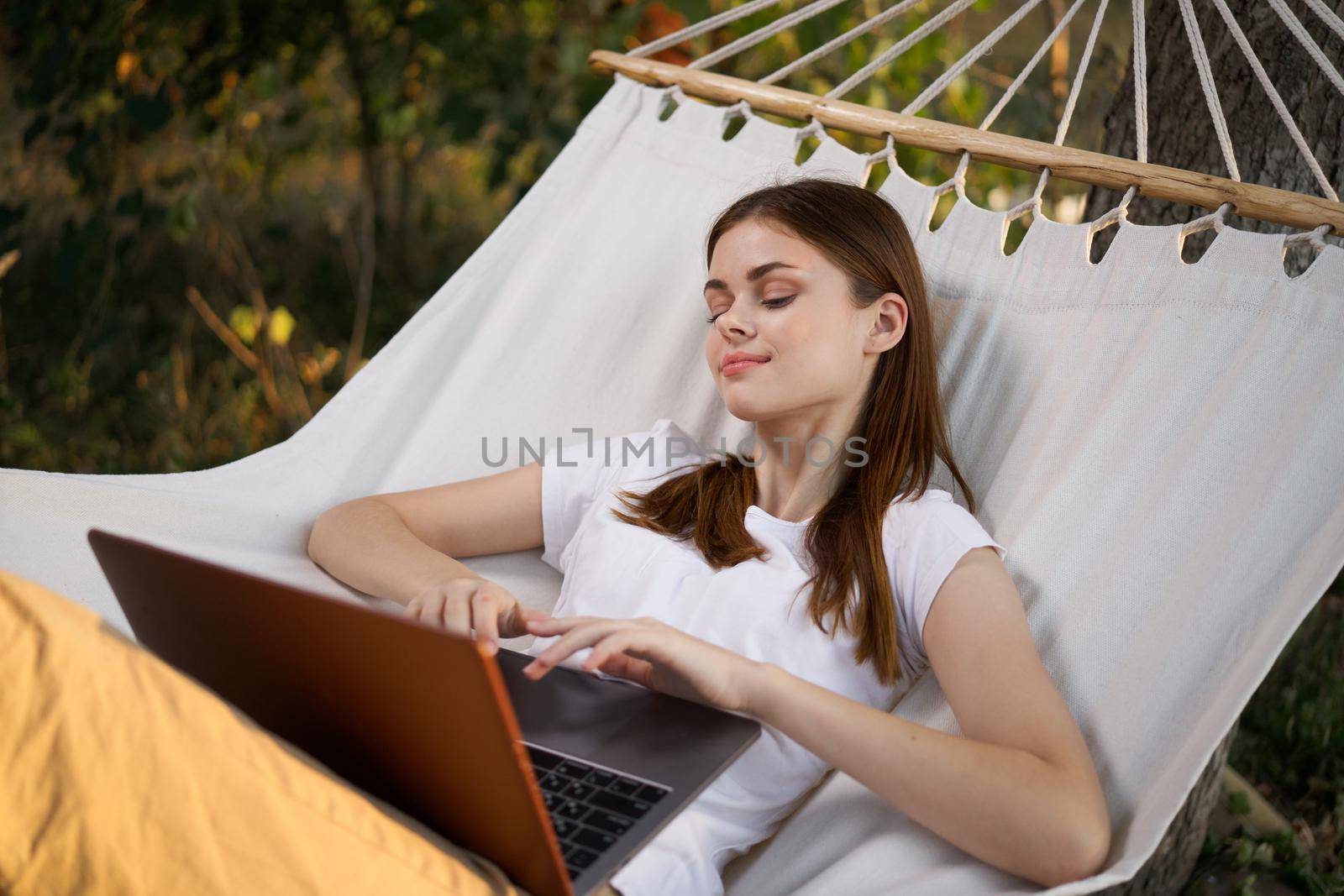 woman working on laptop in nature hammock freelance. High quality photo