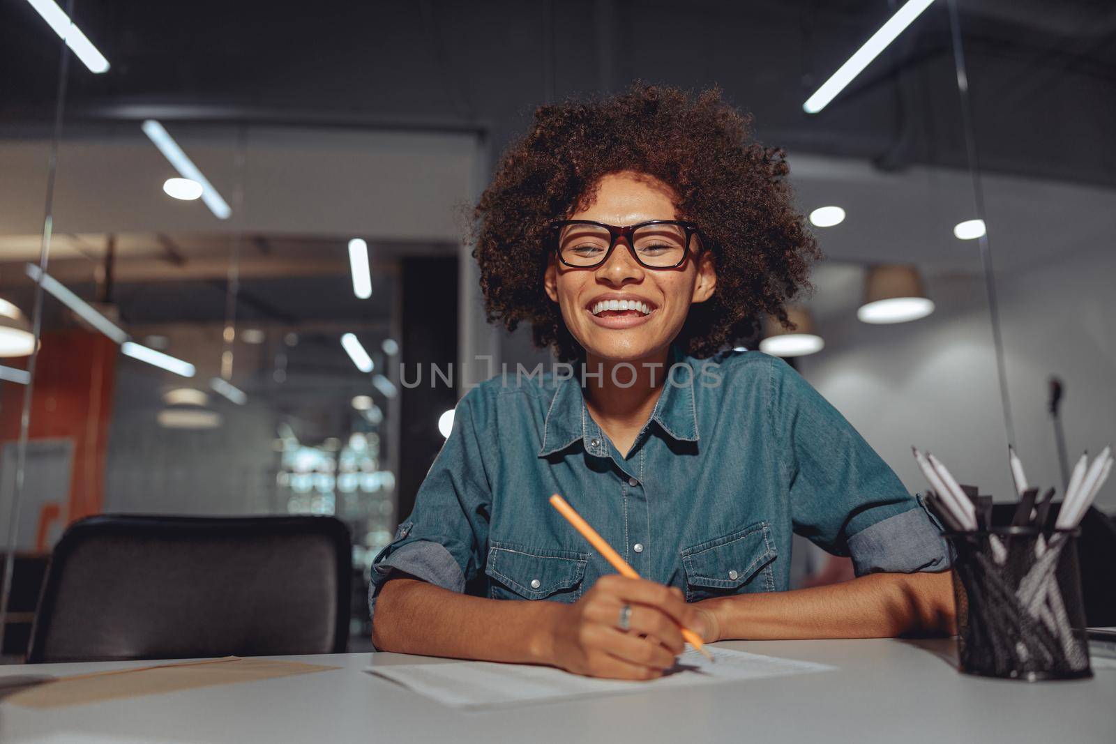 Happy businesswoman in glasses sitting at workplace and working with documents in the office