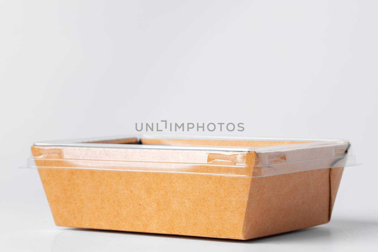 Craft paper disposable box with plastic cover on grey background, copy space, close up