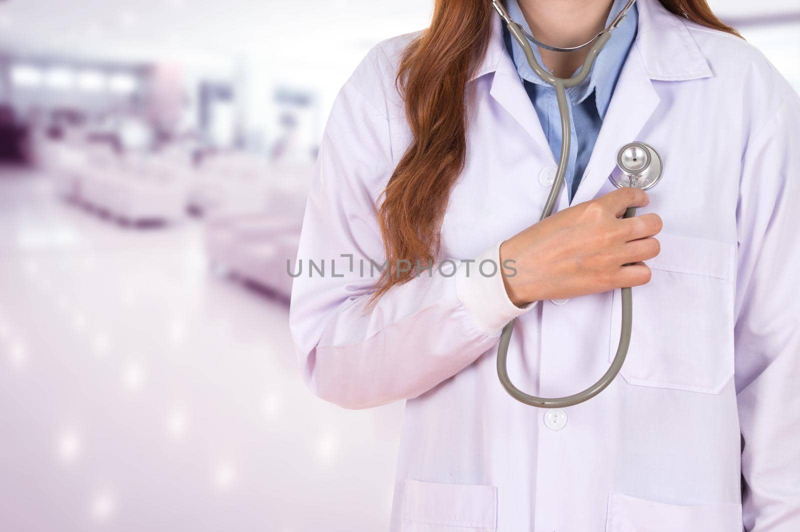 female doctor listening his heart with stethoscope in hospital background