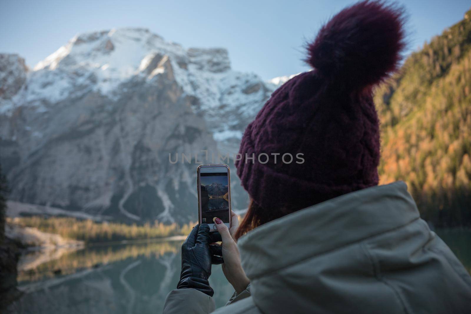 Dolomites nature. Lago di braies lake. Huge beautiful mountains. A woman in a purple hat taking a photo on the view. Wide shot
