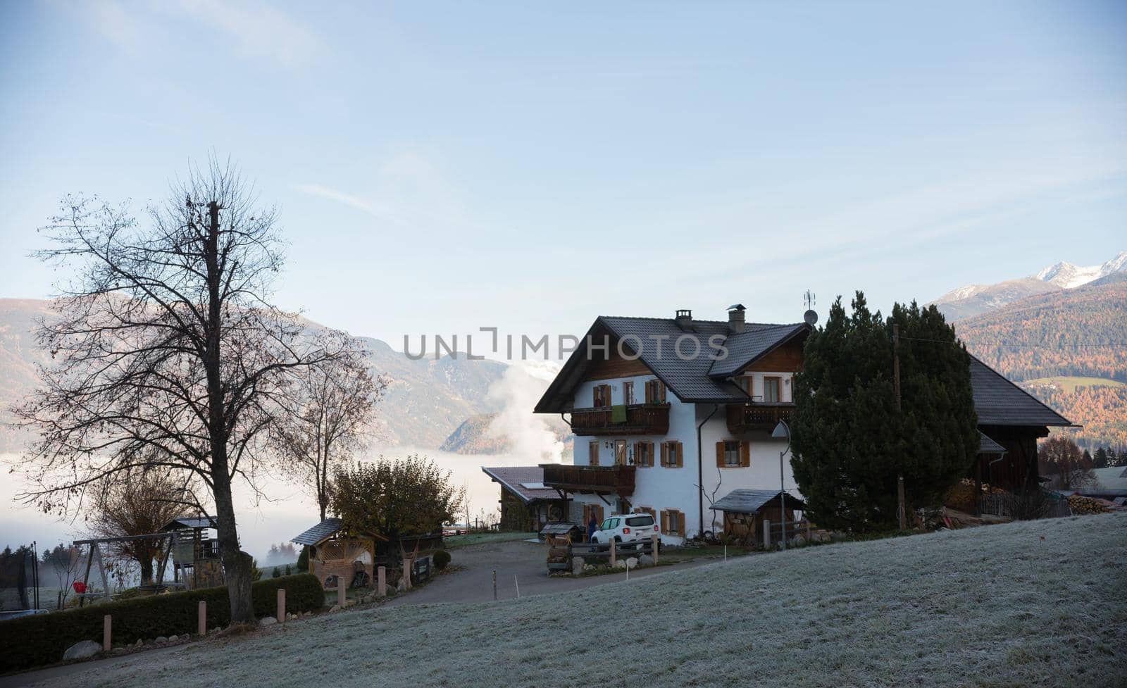 Dolomites. A beautiful house with a huge mountains and fog on a background. Mid shot