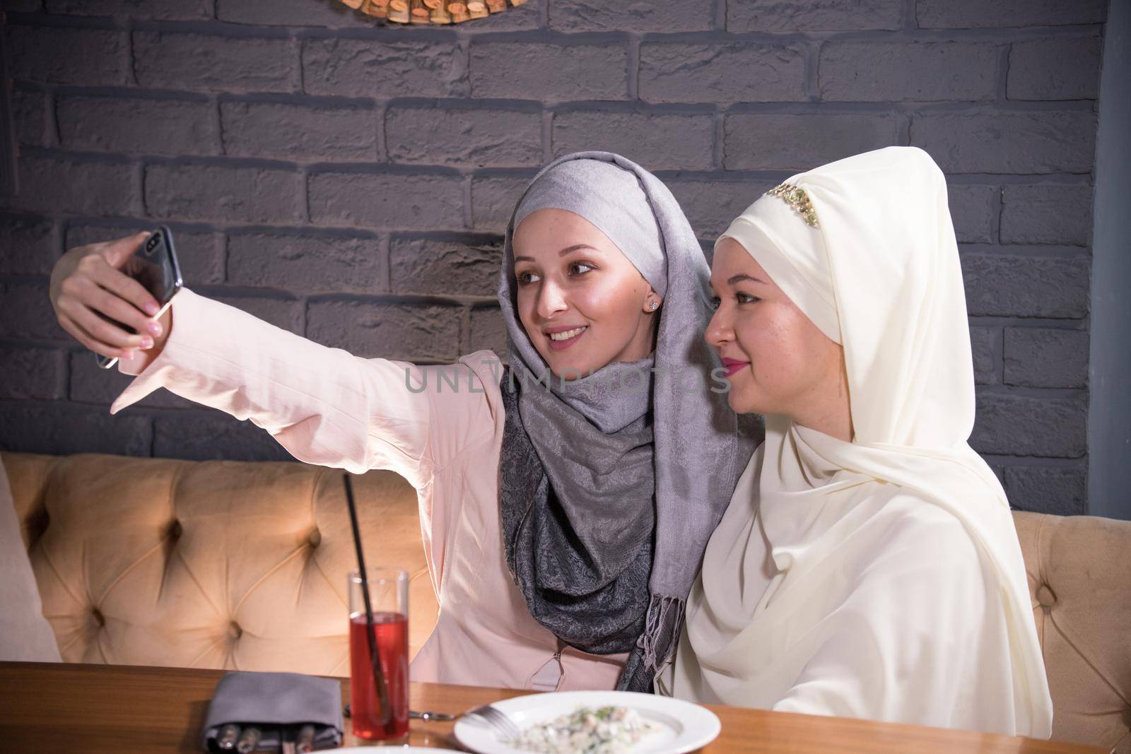 Girls in hijabs are photographed in a cafe, telephoto shot