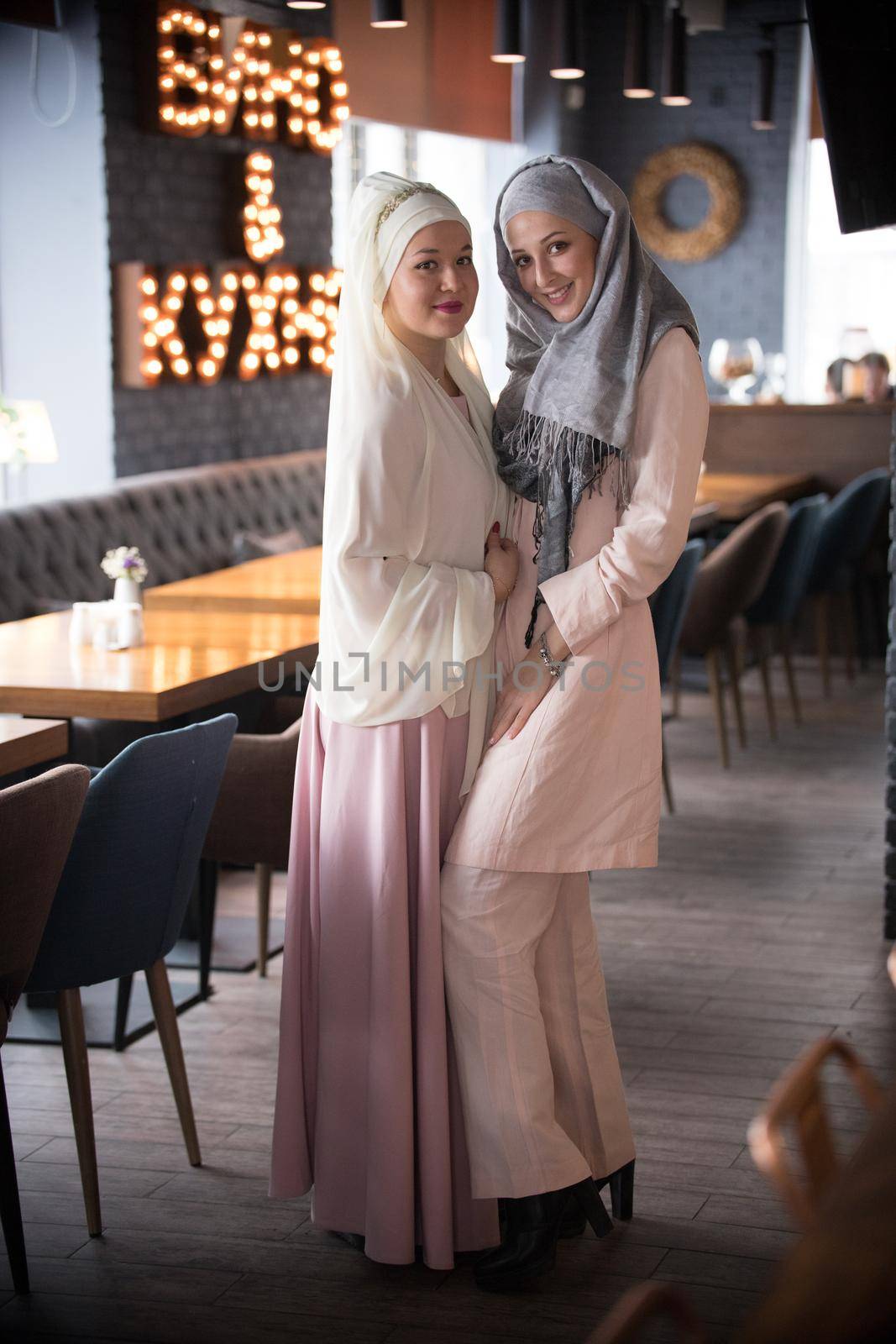 Two young muslim women standing in the cafe. Portrait