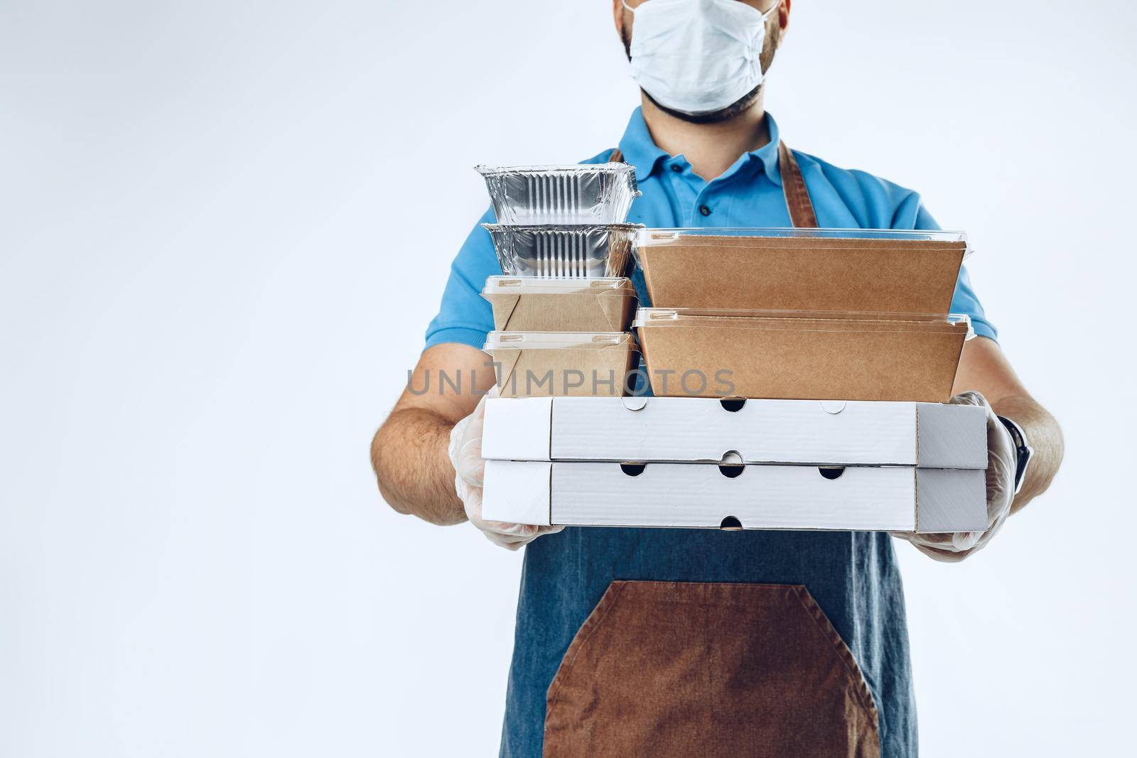 Unrecognizable man in blue polo shirt with food delivery orders against light grey background