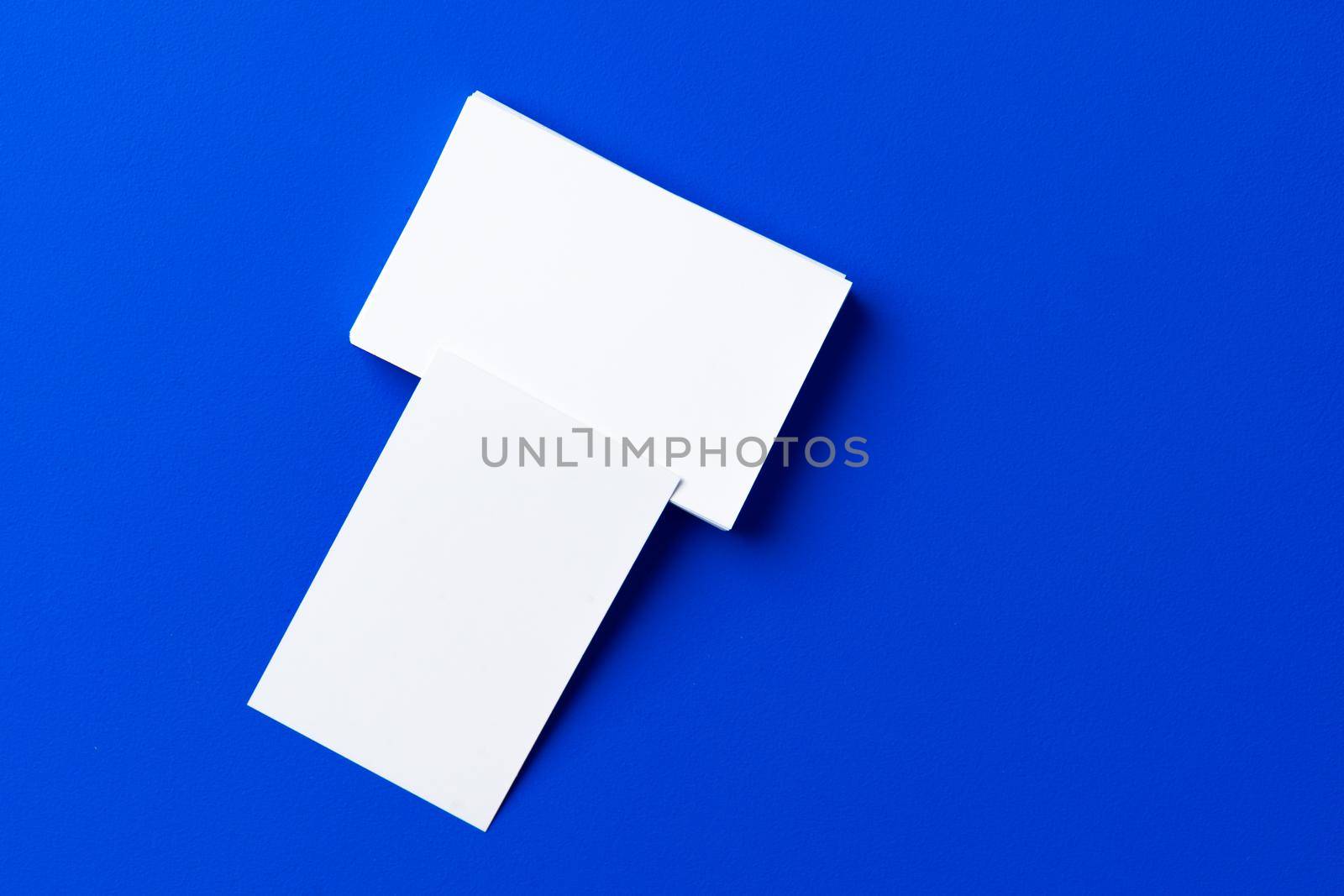 Blank white businesscards on classic blue background, copy space