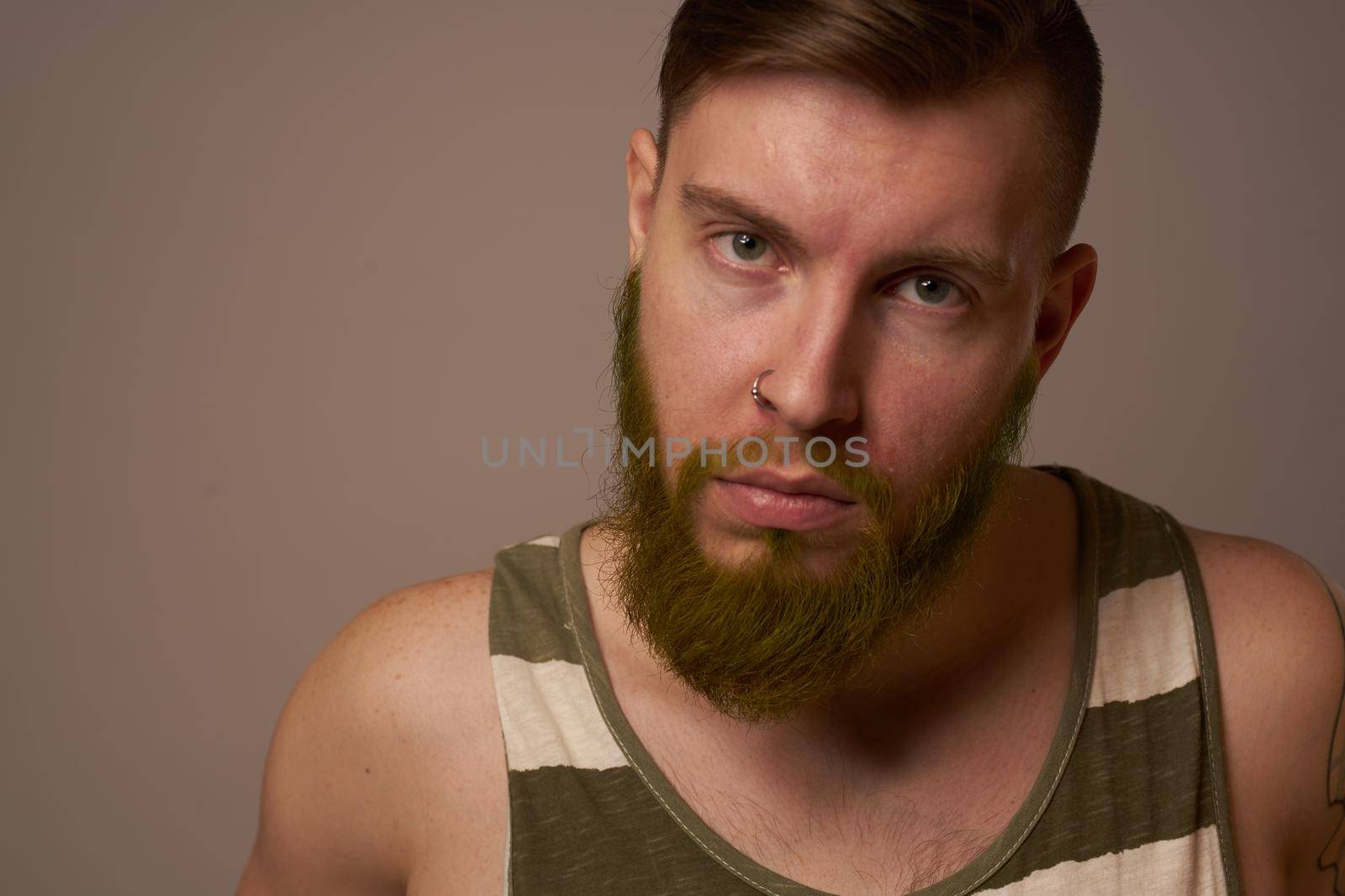 bearded man in striped t-shirt with tattoos posing studio. High quality photo